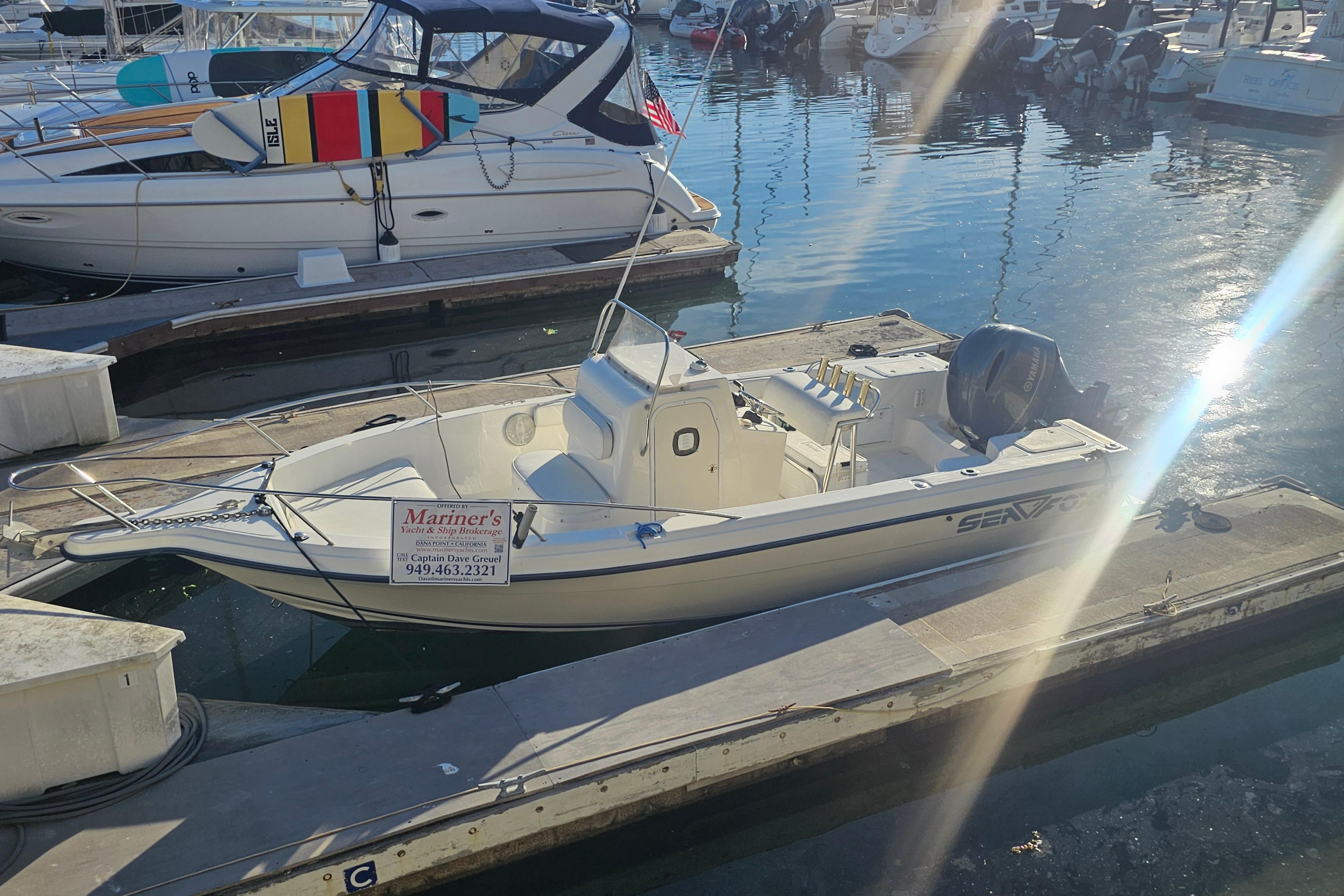 2002 Sea Fox 210 Center Console boat docked at marina under sunlight.