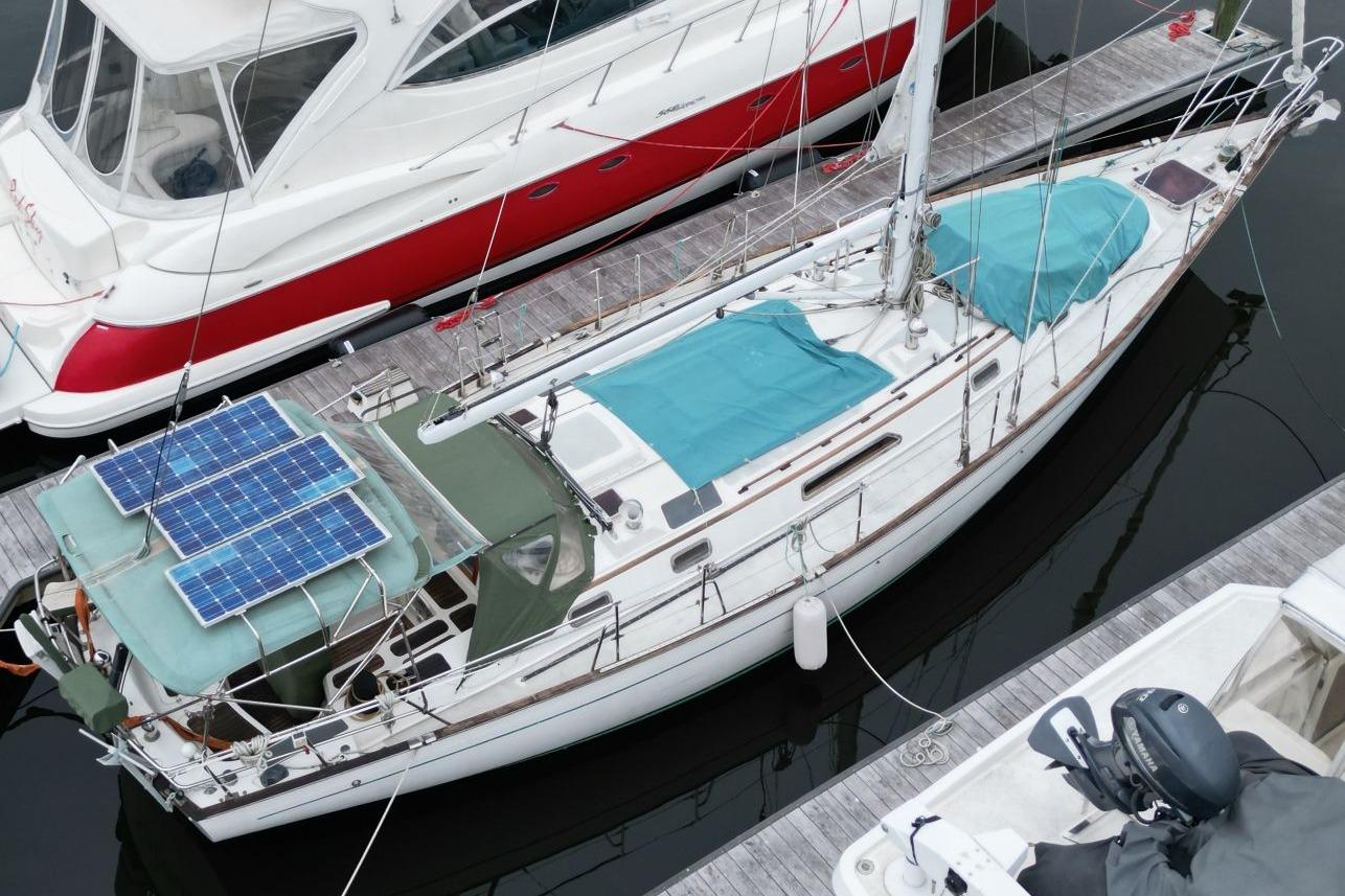 Aerial view of 1985 Passport 47 sailboat with solar panels docked at marina.