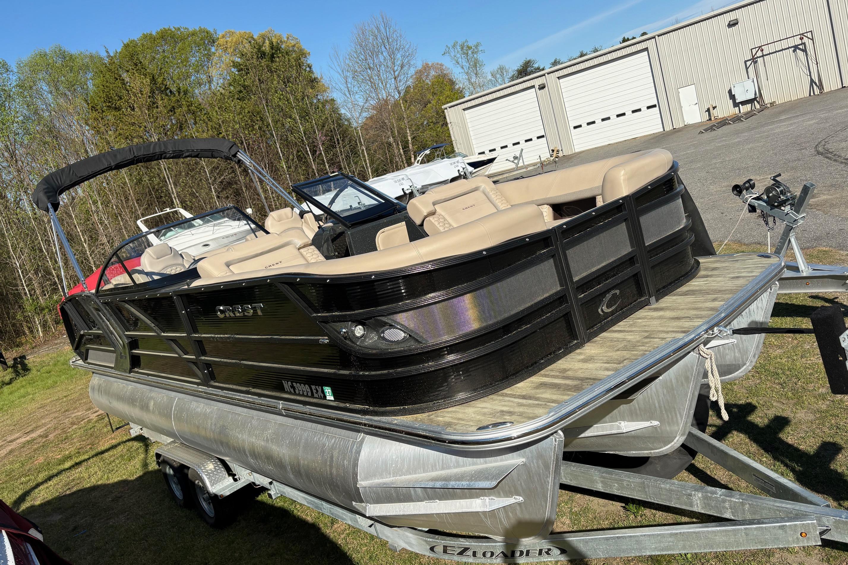 2022 Crest Continental 250 pontoon boat on trailer, parked outdoors near storage facility.