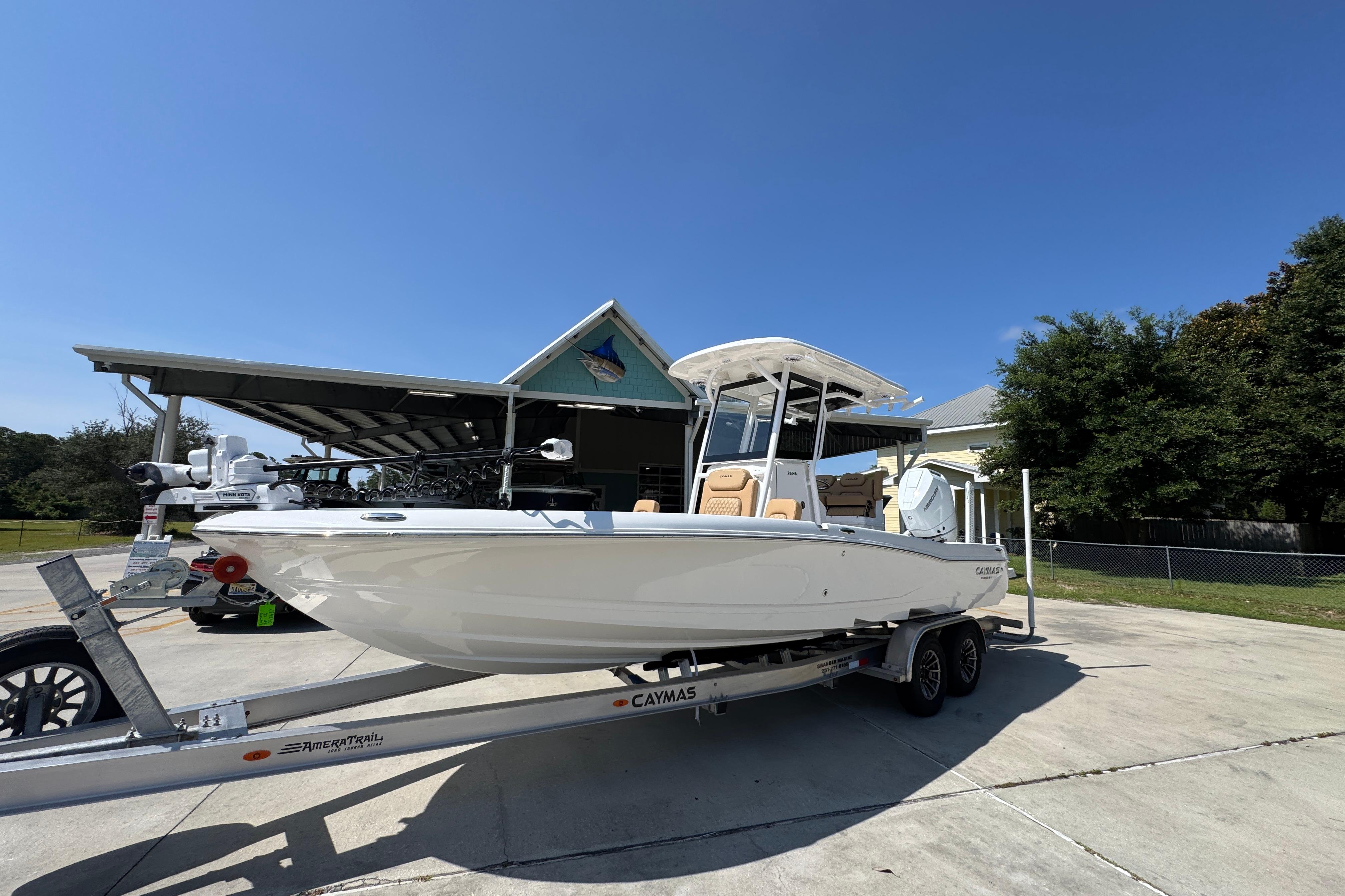 2027 Caymas 26 HB boat on trailer, parked outdoors under clear blue sky.