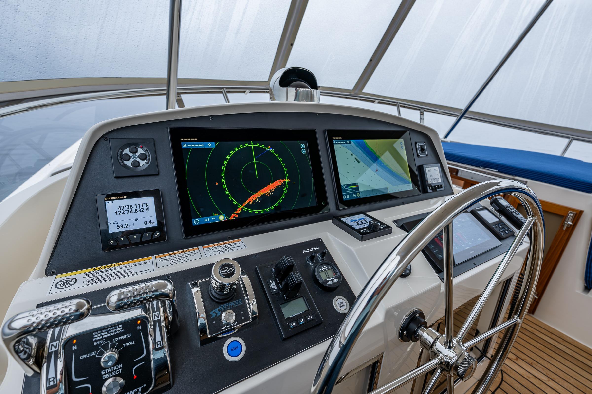 Pilothouse of 2026 Fleming 55 yacht with advanced navigation systems and steering wheel.