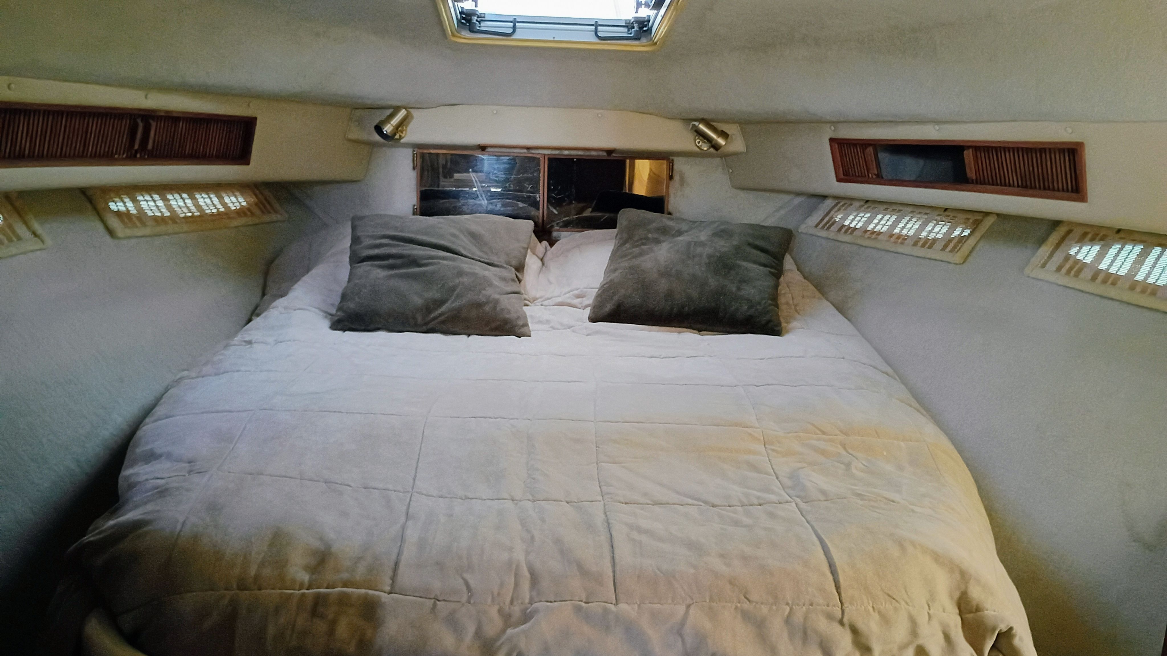 The image shows a cozy cabin with a double bed, two pillows, and a skylight.