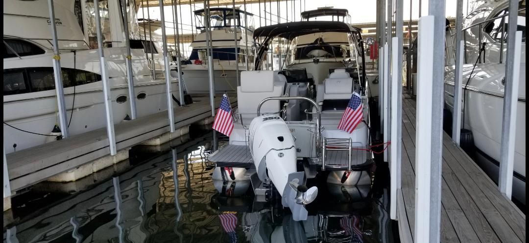 2021 Avalon Excalibur Elite boat docked with US flags.