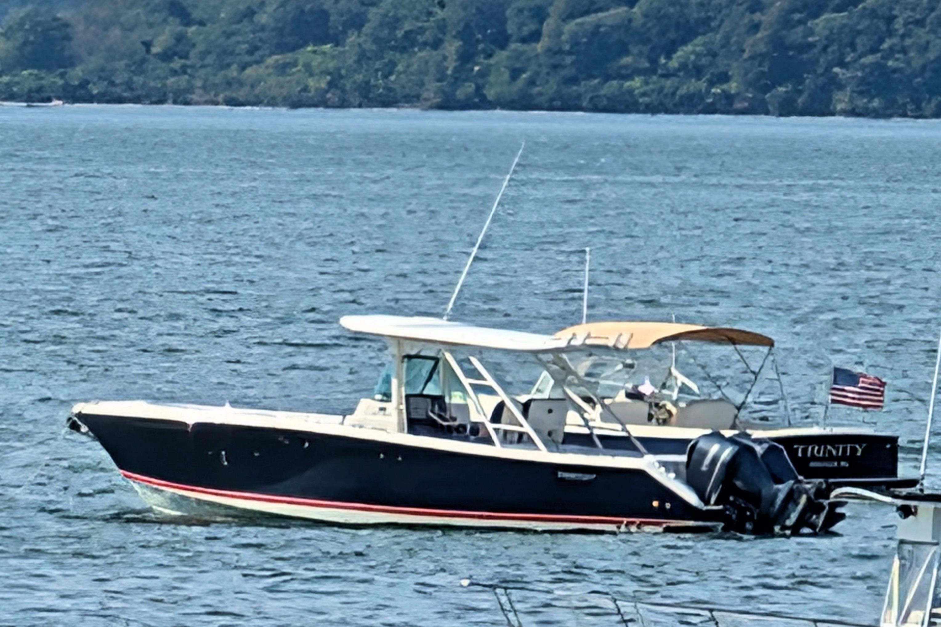 2013 Pursuit ST 310 Sport boat on water, with American flag, scenic background.