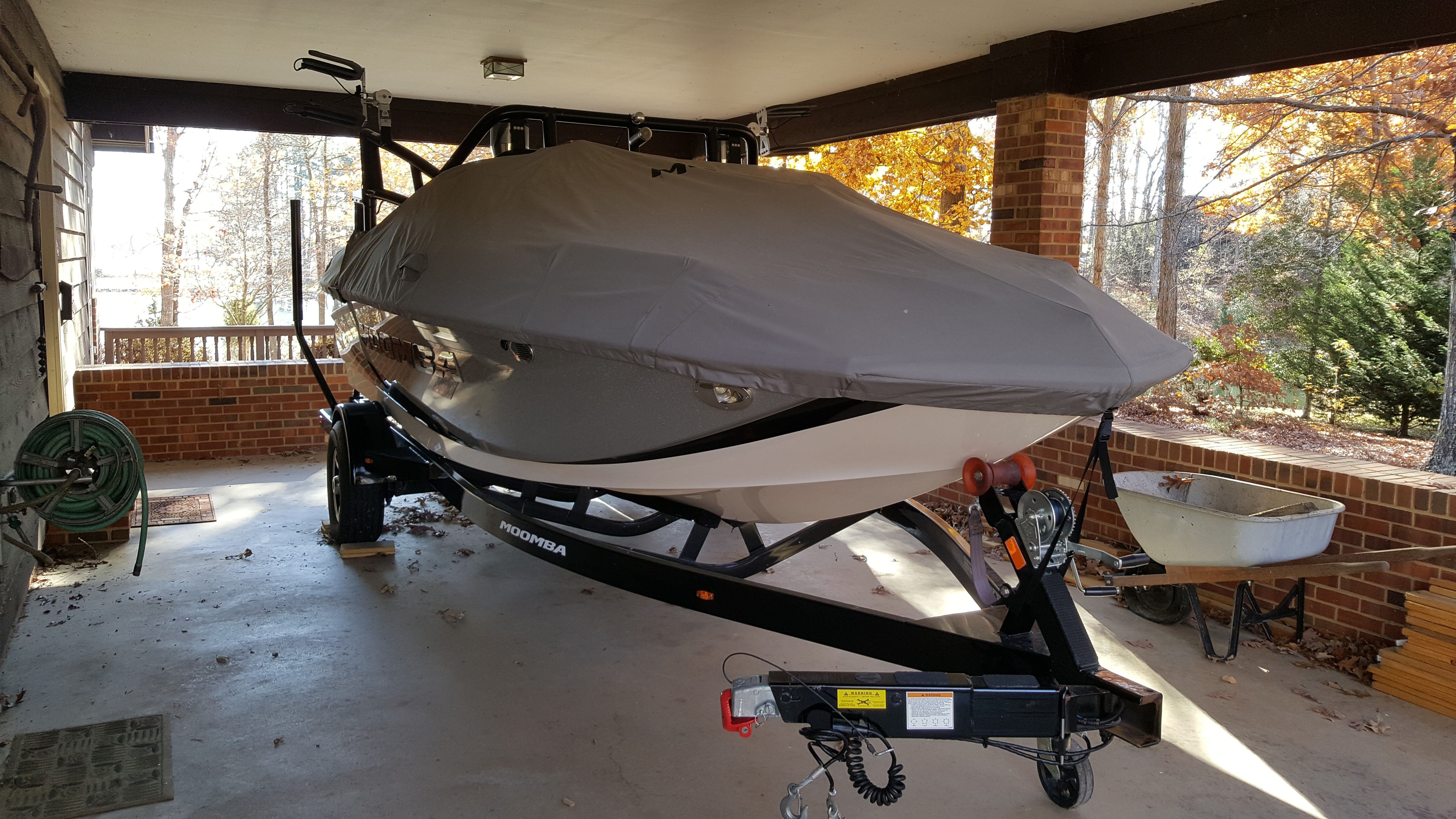 A 2016 Moomba Mondo boat on a trailer, covered, parked under a carport.