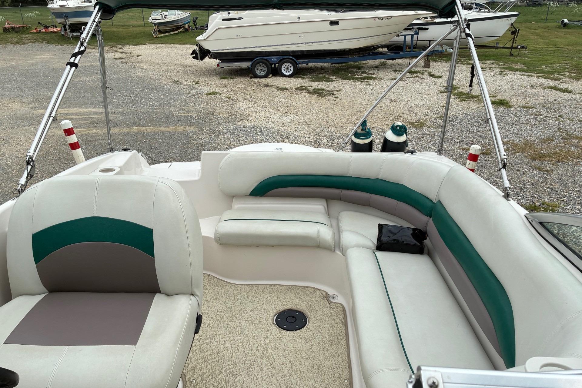 2003 Hurricane 234 SD boat interior with white and green seating, parked on gravel.