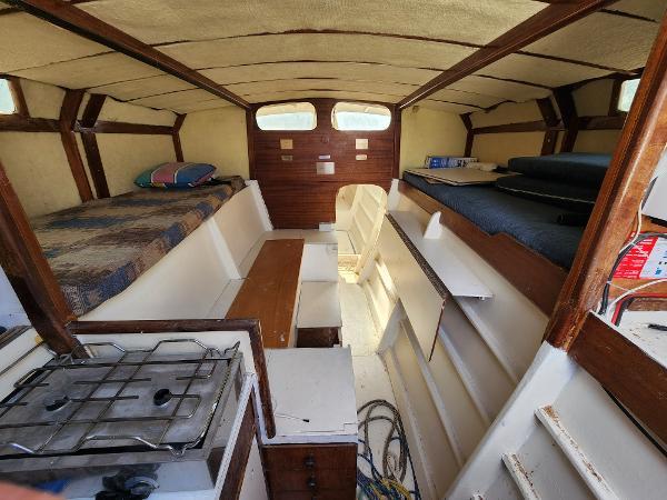 Interior of a 1985 Crowther Buccaneer boat with cozy sleeping and cooking areas.