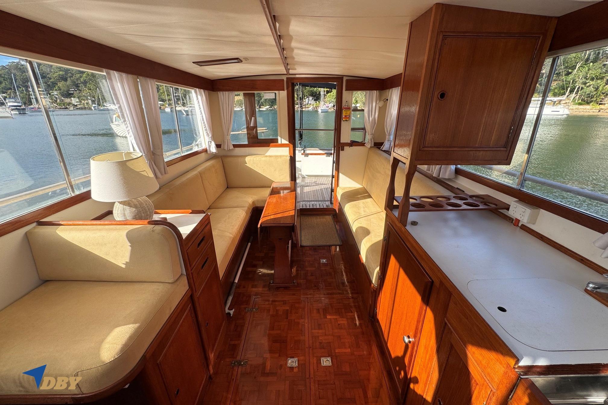 Interior of a 1980 Grand Banks 32 Sedan yacht with wooden furnishings and scenic water views.