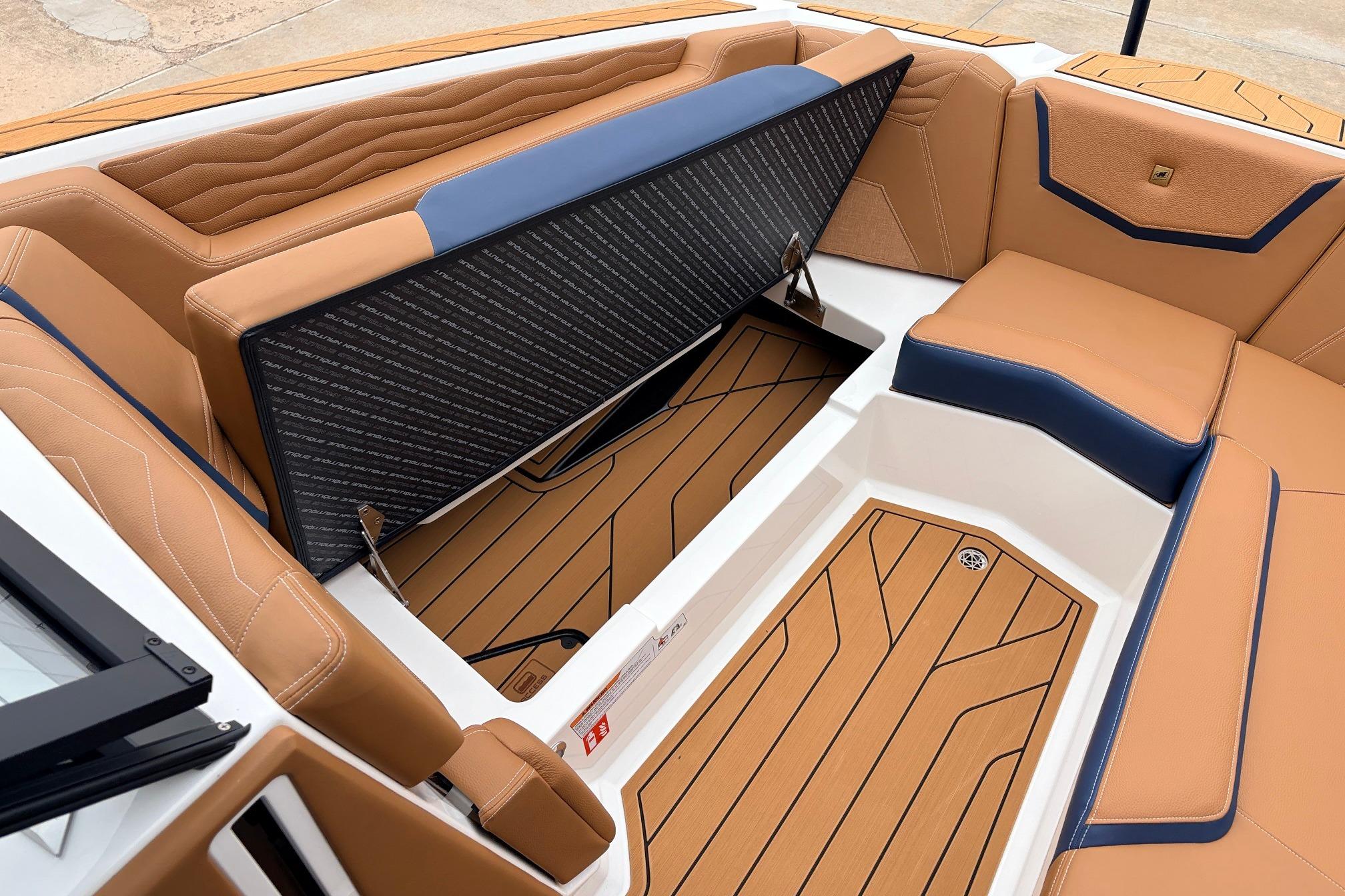 2026 Nautique Super Air Nautique G25 interior with tan and blue seating, open storage compartment.