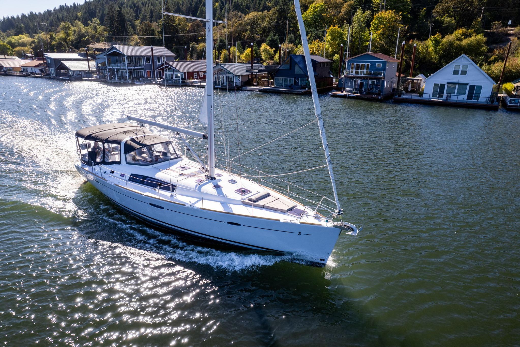 2013 Beneteau Oceanis 50 sailing on a scenic river near waterfront homes.