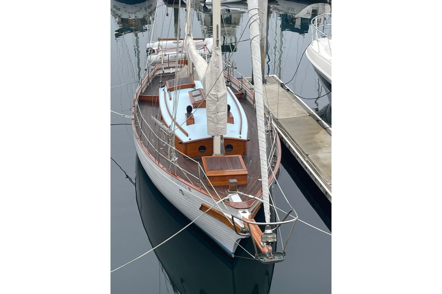 Vintage 1965 sailboat docked, featuring wooden deck and classic design.