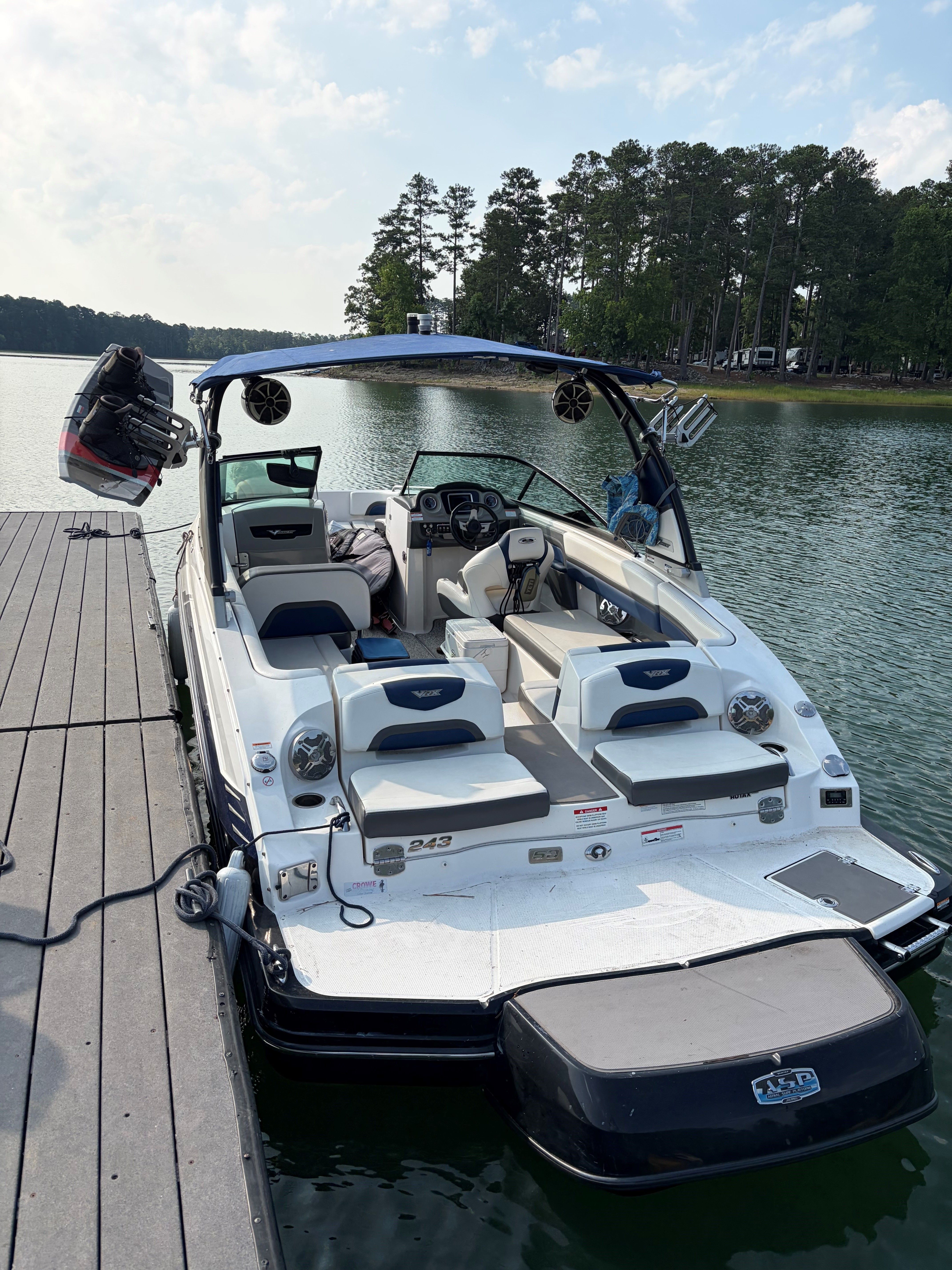 A 2015 Chaparral Vortex 243 VRX docked. It features a white exterior and a blue sunshade.