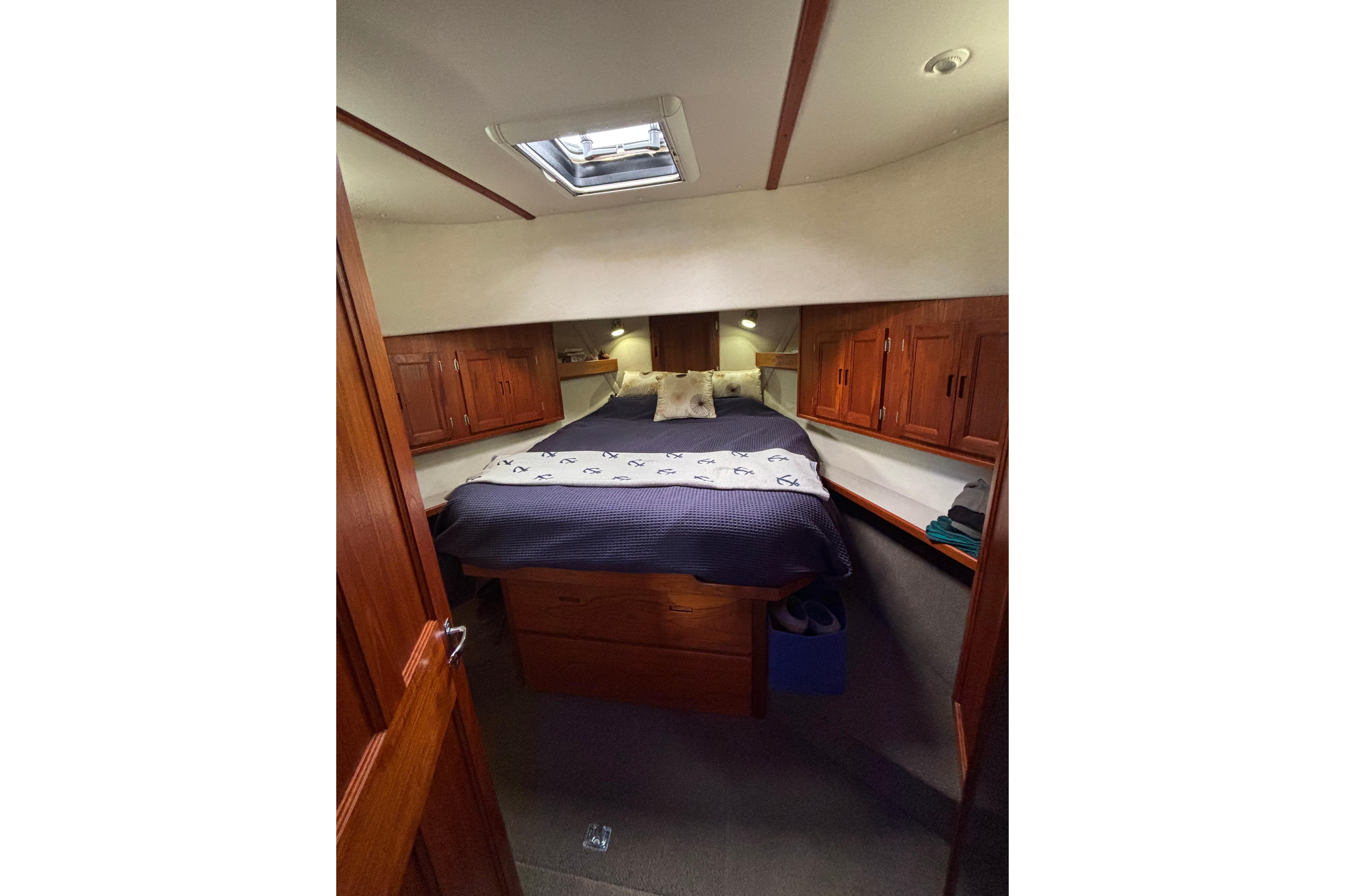 Cozy cabin interior of a 2004 Nordic Tug 37 with wooden cabinetry and a skylight.