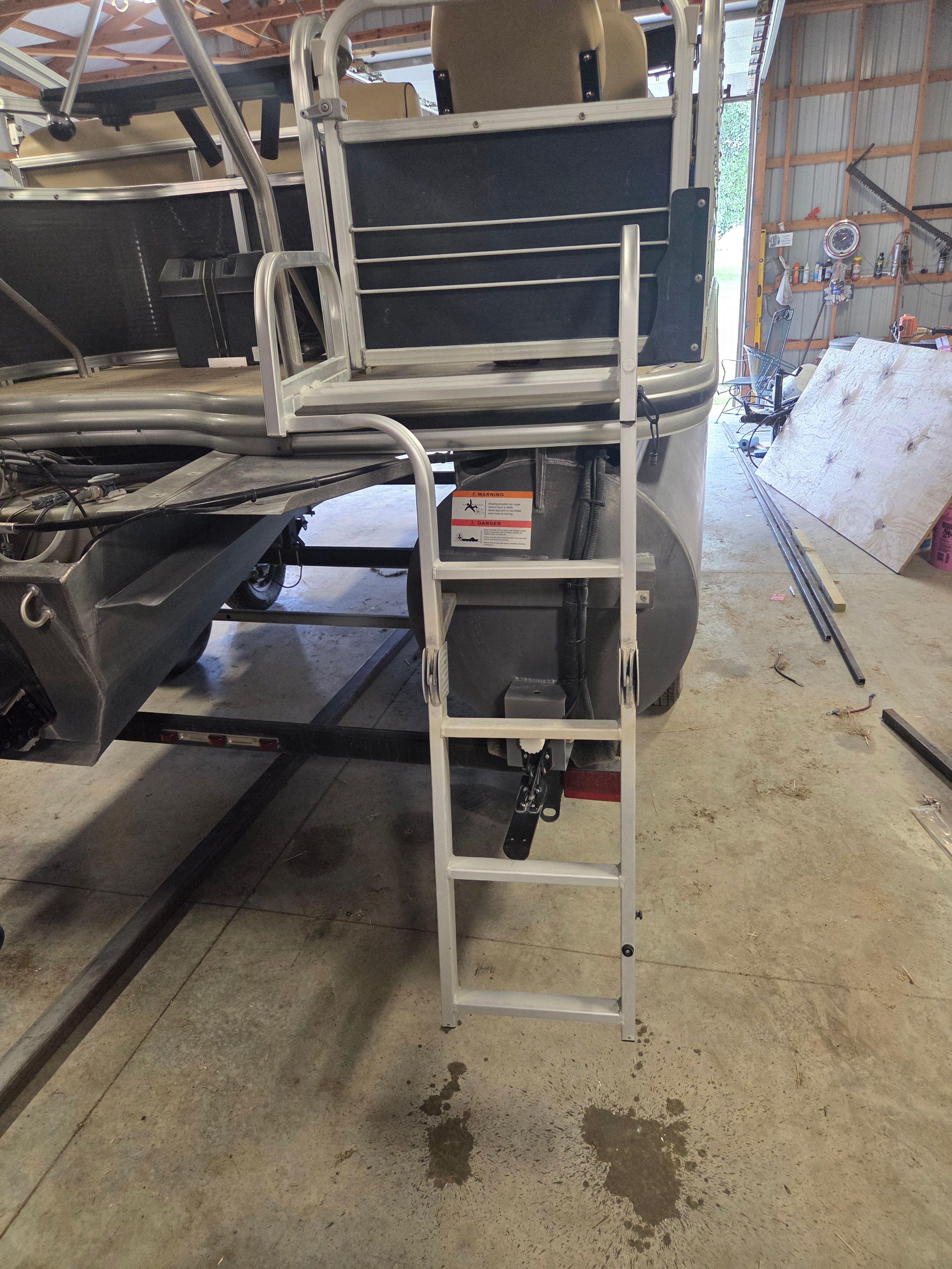 A boat with a ladder at the stern, parked in a workshop.