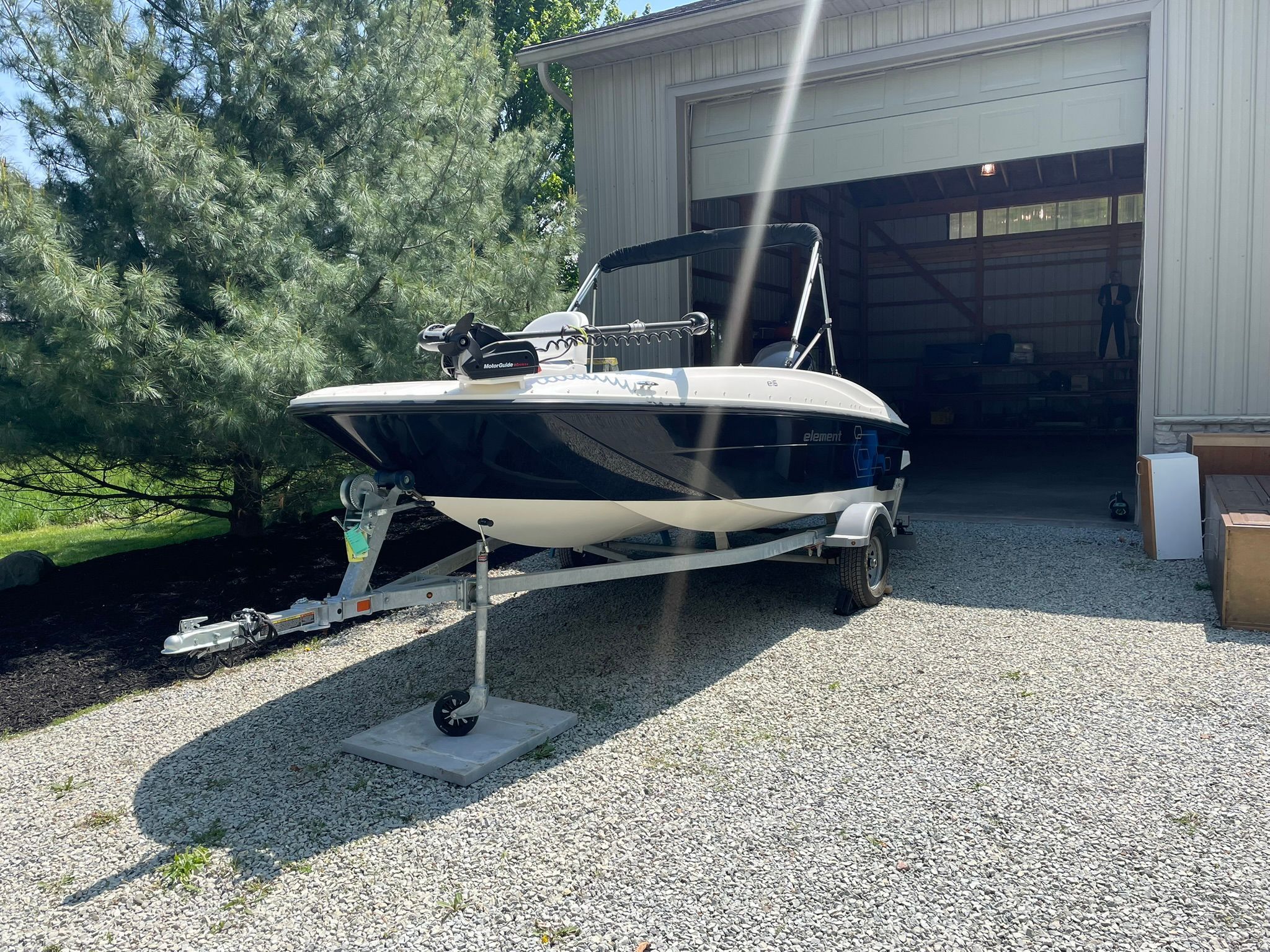 A 2018 Bayliner 160 Bowrider on a trailer in front of a garage.
