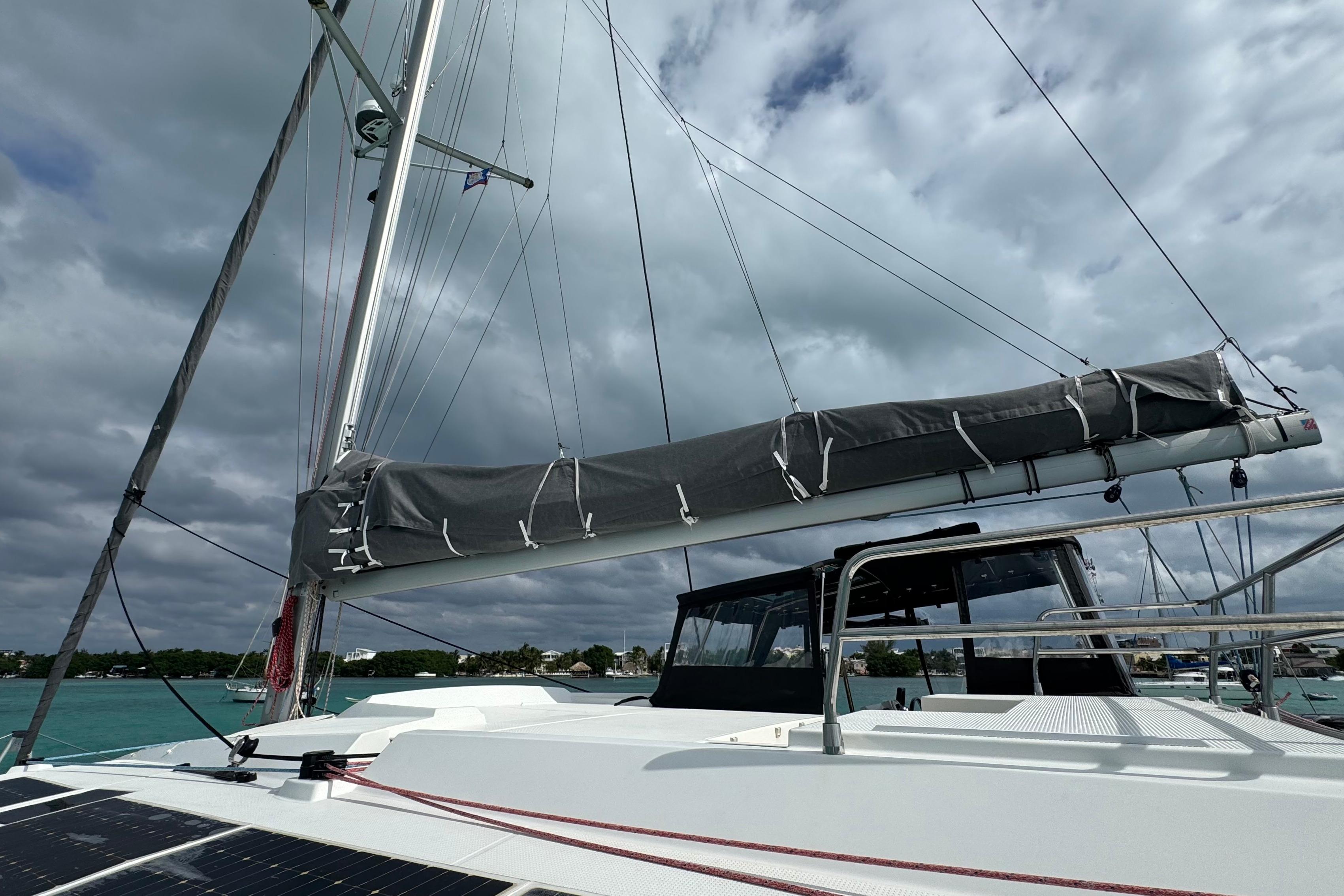 2020 Fountaine Pajot Saona 47 catamaran with sails down, anchored under cloudy skies.