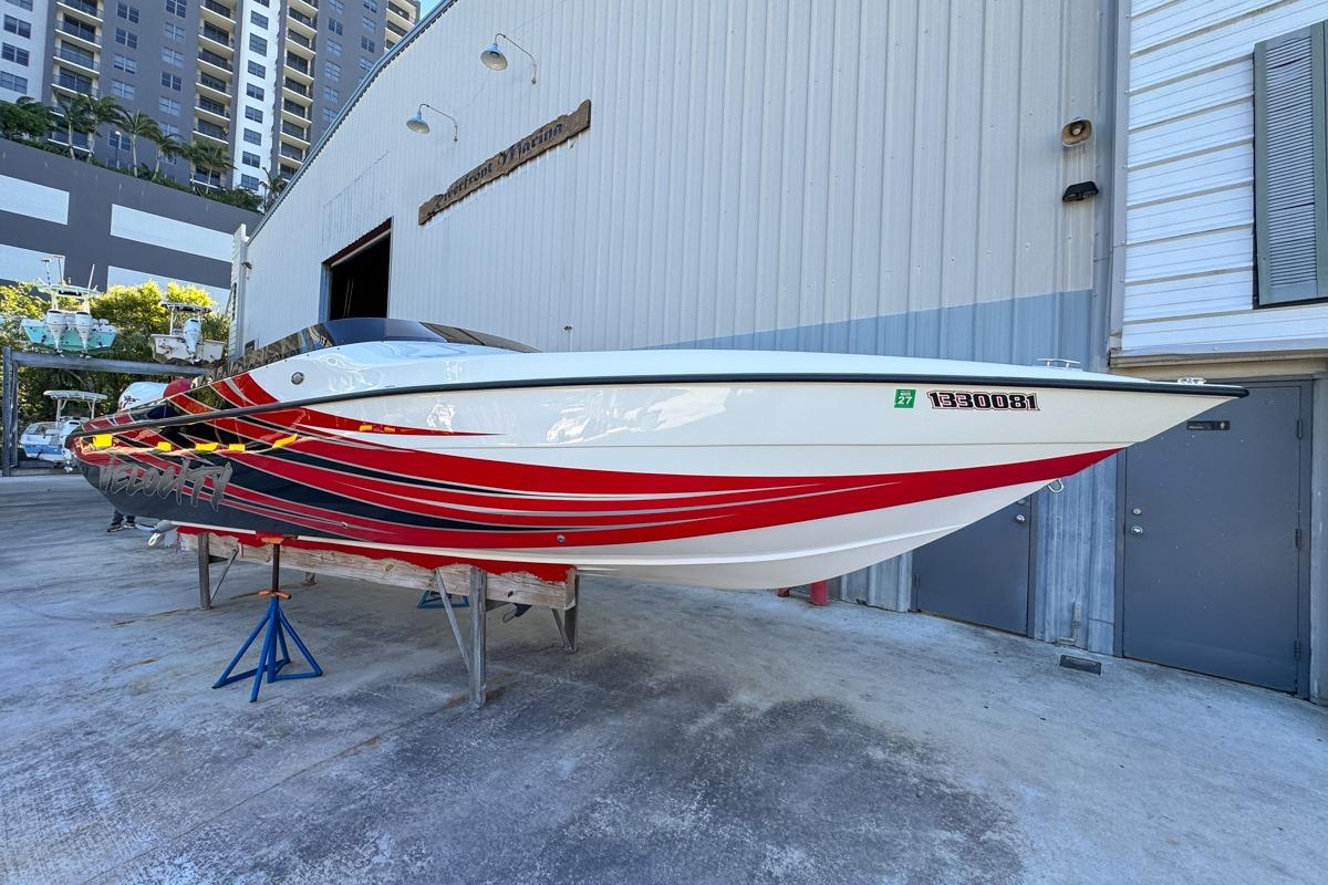 2022 Velocity 290sc speedboat with red and black stripes, displayed on stands outside a marina.