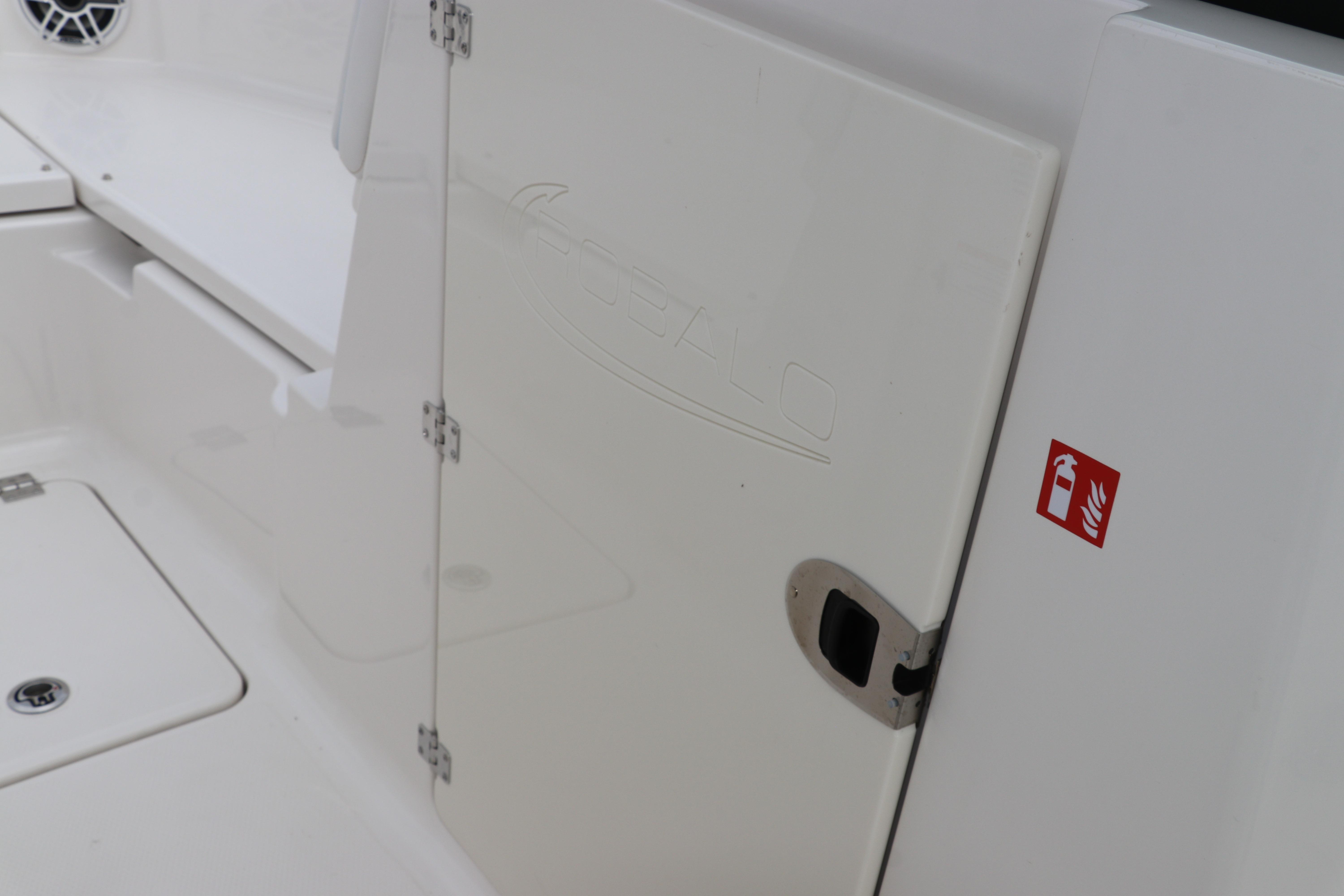2026 Robalo R257 Dual Console boat interior with storage compartment and fire extinguisher symbol.