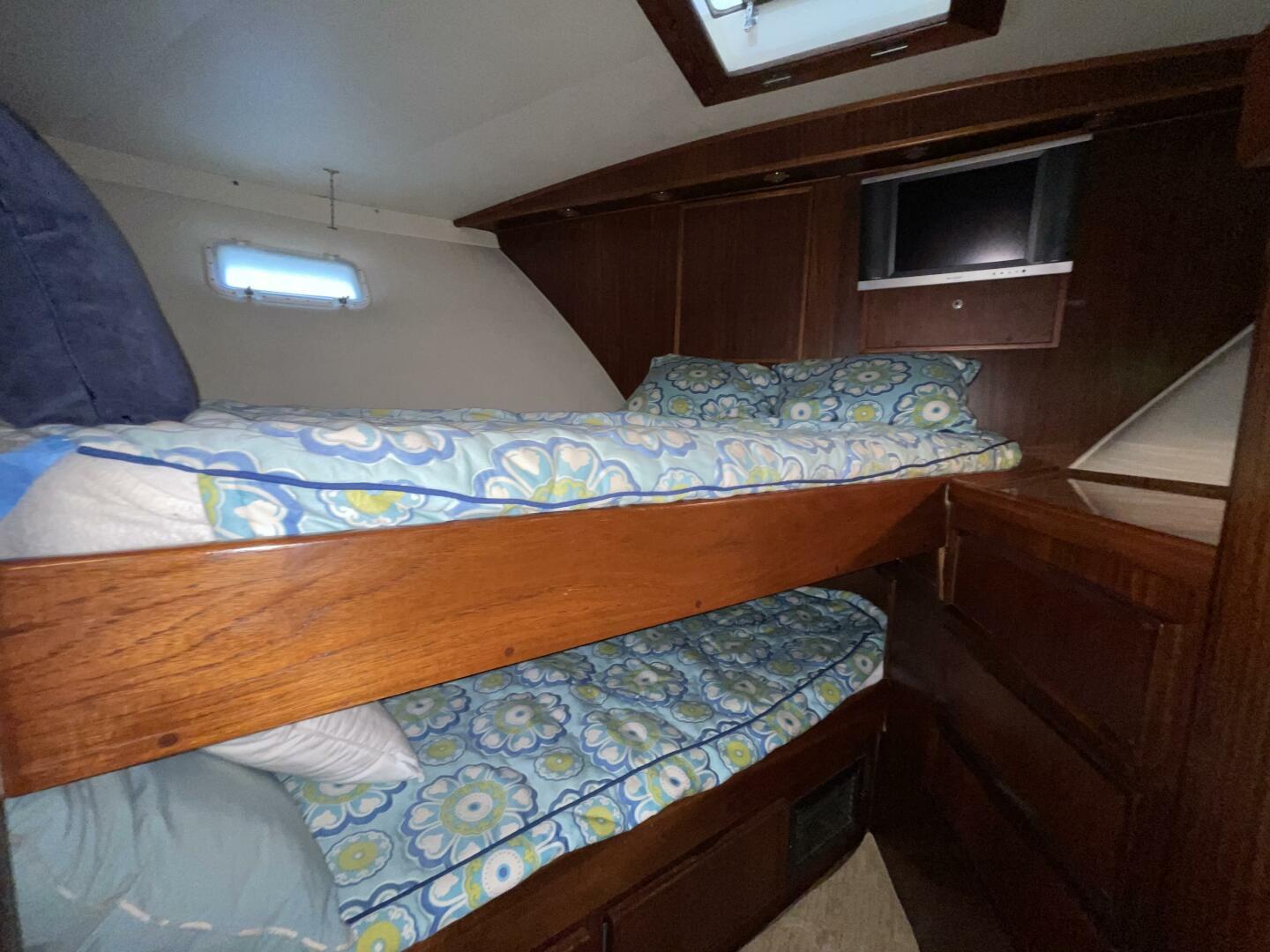 Interior of 1985 Hatteras Enclosed Bridge with bunk beds and floral bedding.