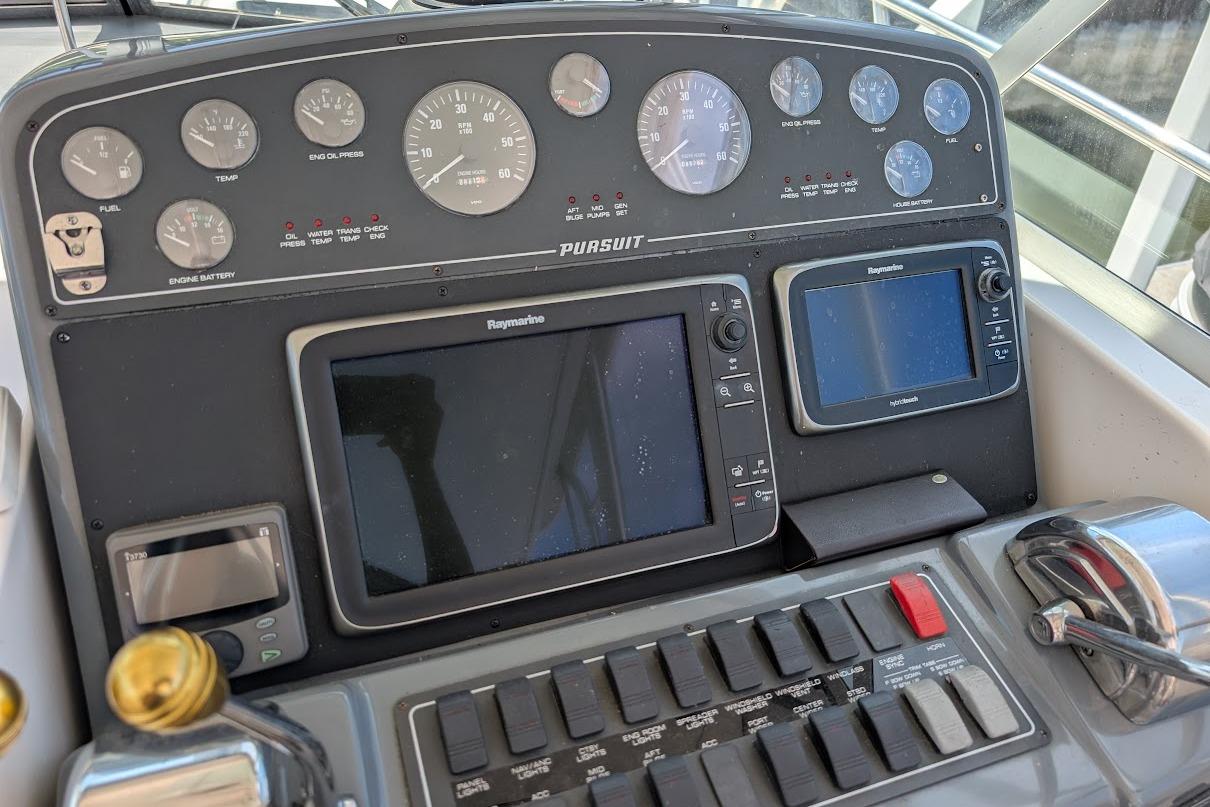 Control panel of a 2000 Pursuit 3400 Express boat with gauges and navigation screens.