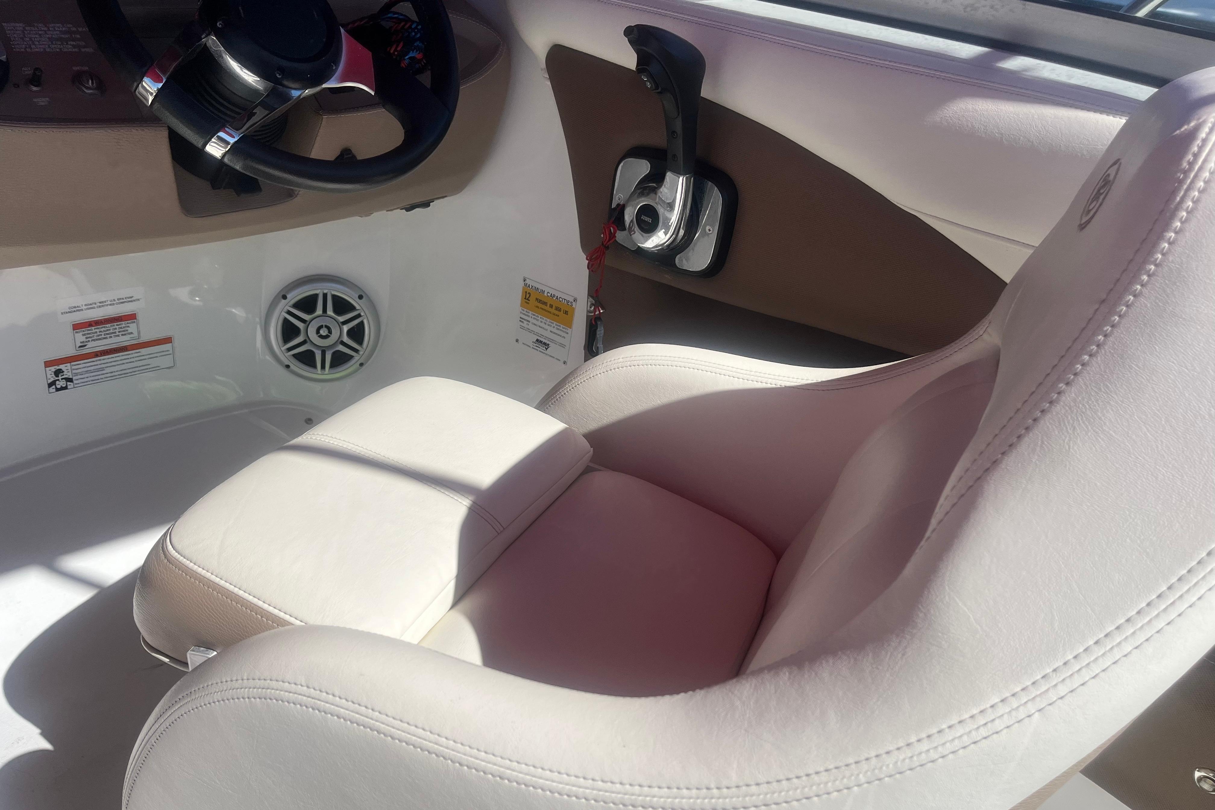 Interior of a 2011 Cobalt 210 boat featuring a white captain's seat and control panel.