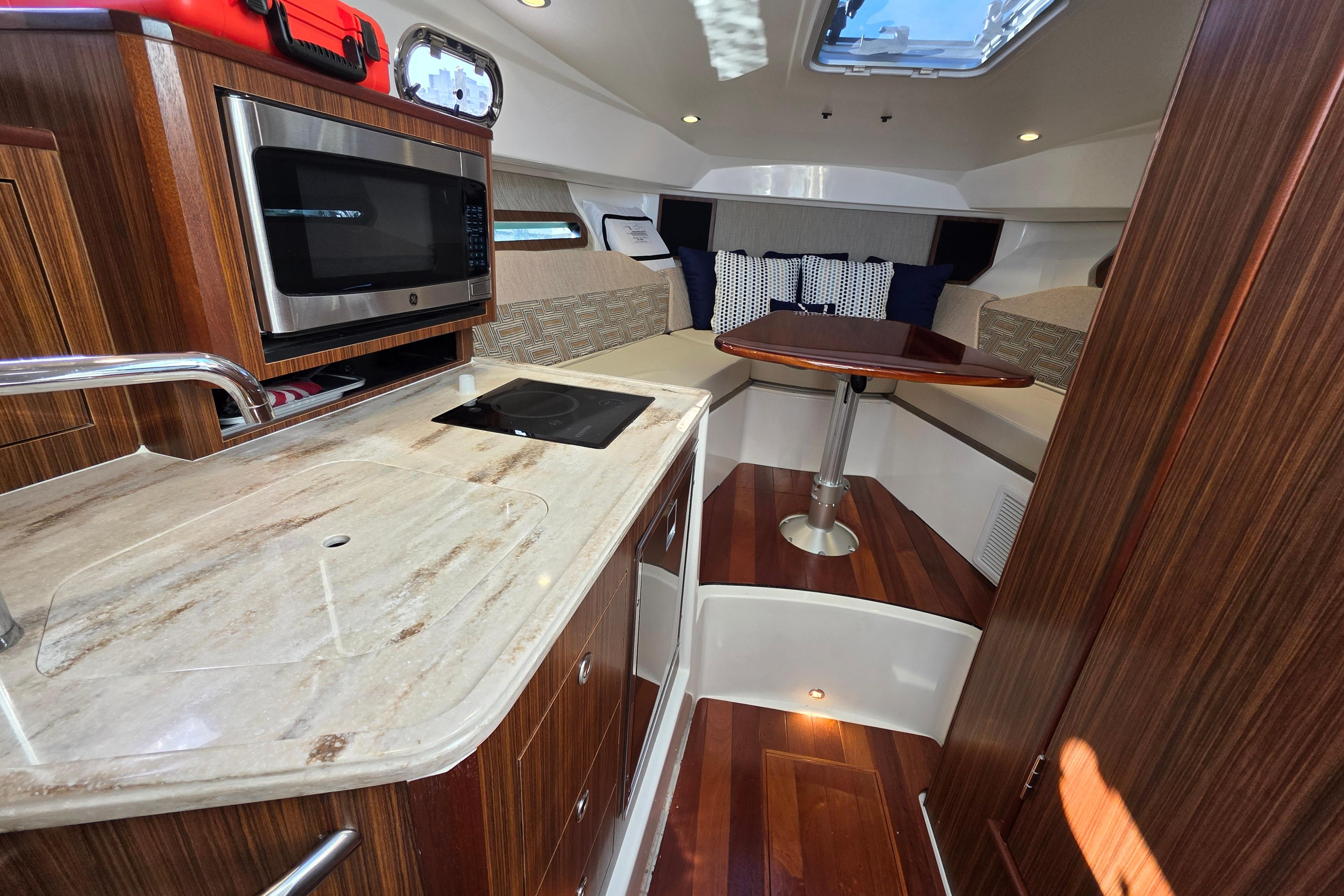 2024 Pursuit OS 325 Offshore interior with kitchenette and seating area.