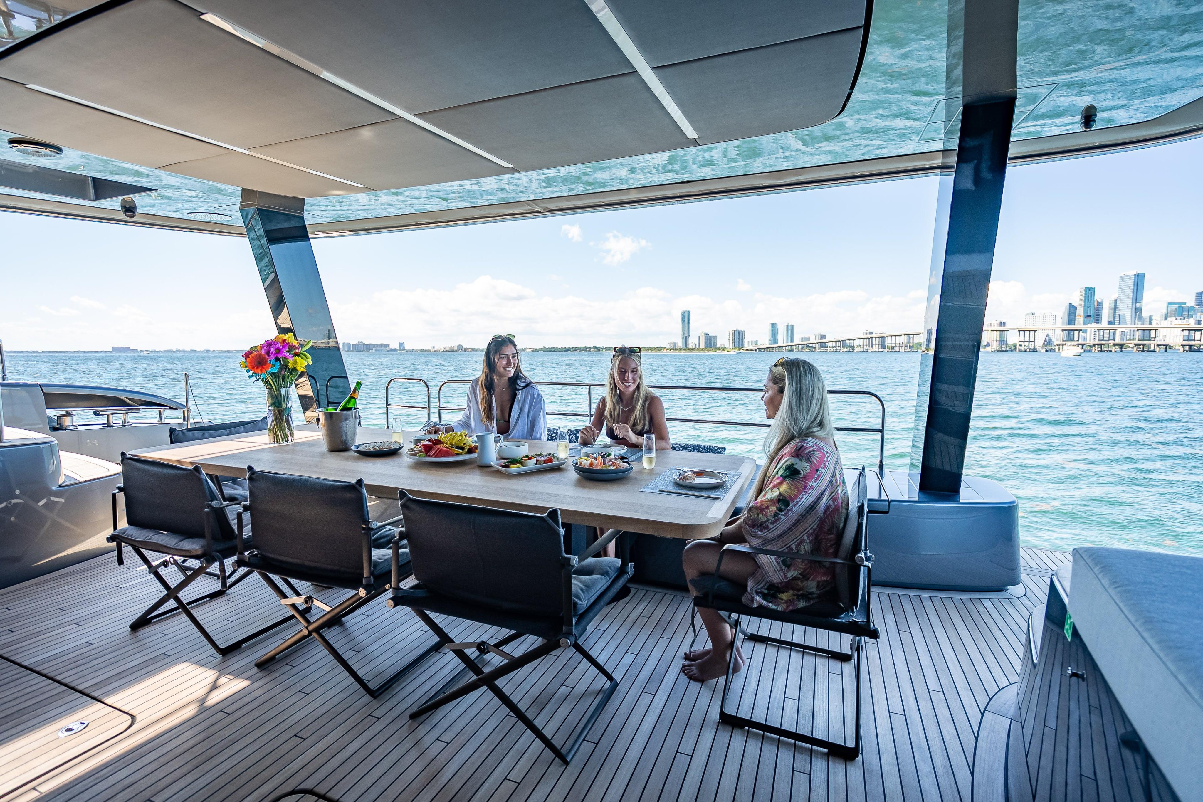 Luxurious Sunreef 60 Power yacht deck with dining area, ocean view, and city skyline.