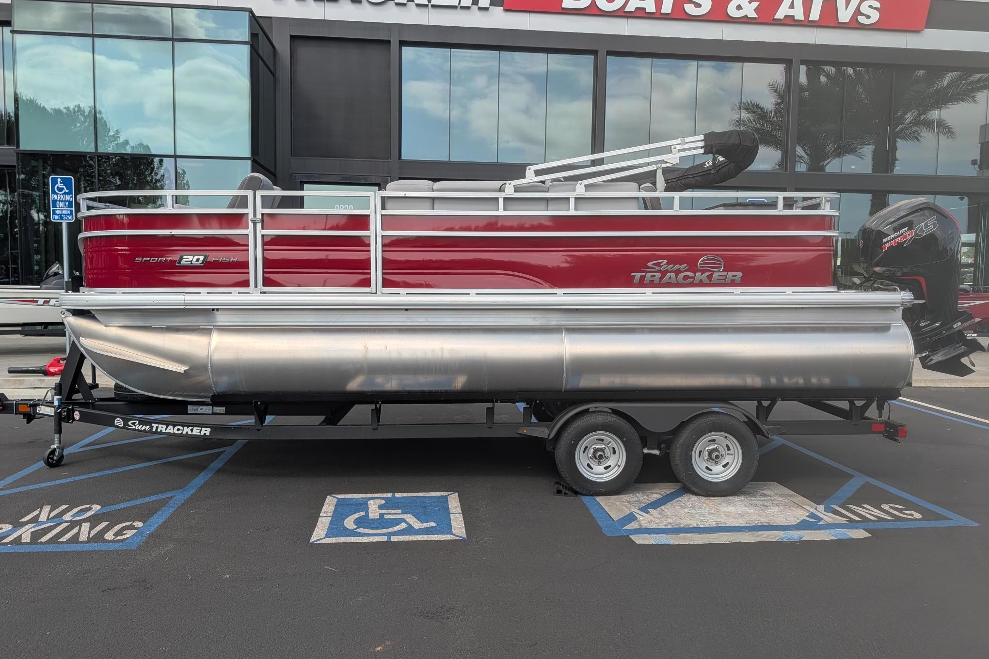 2026 Sun Tracker SportFish 20 DLX pontoon boat on trailer, parked outside dealership.