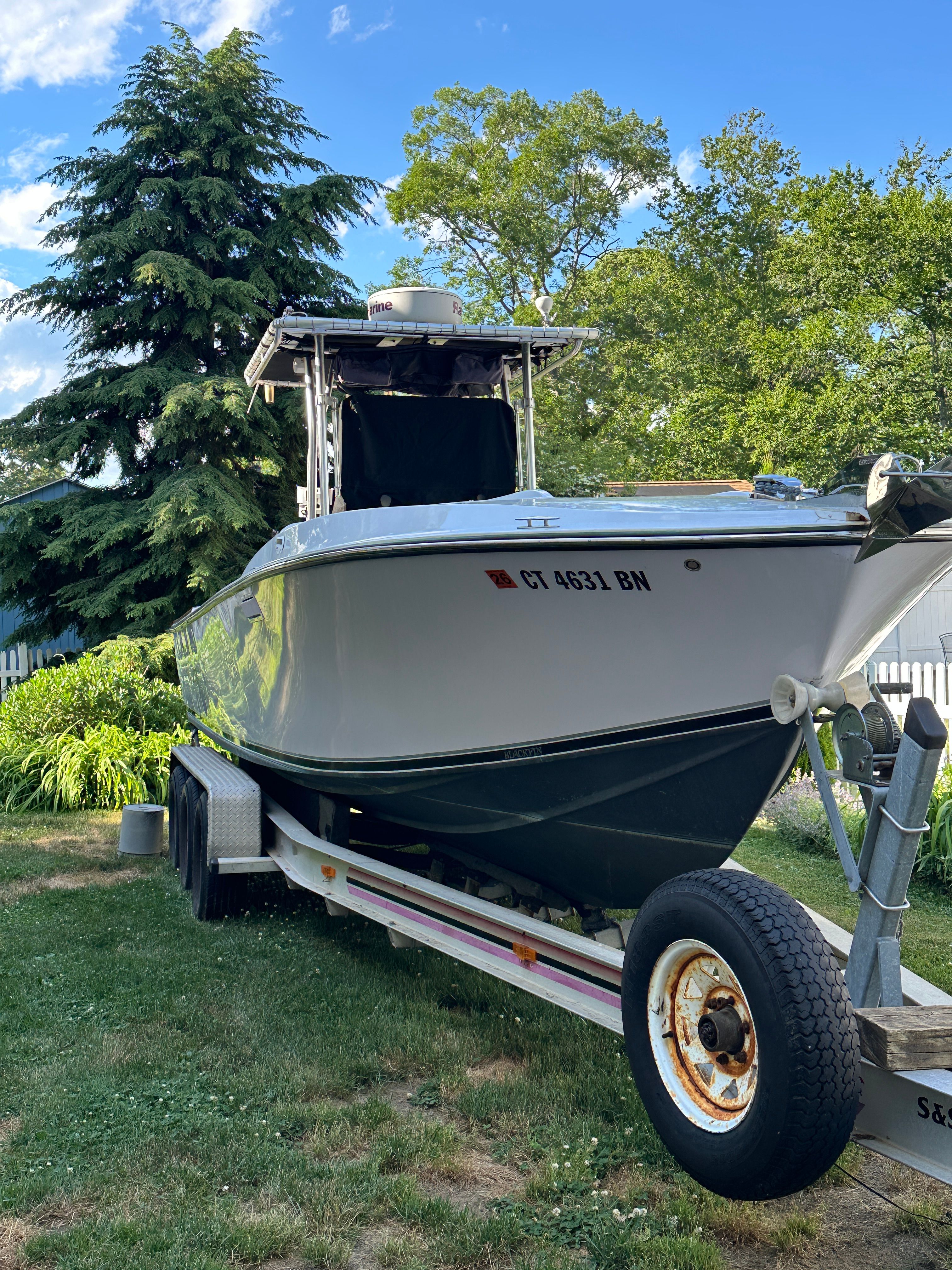 A 1976 Blackfin Fisherman boat is on a trailer in a grassy area.
