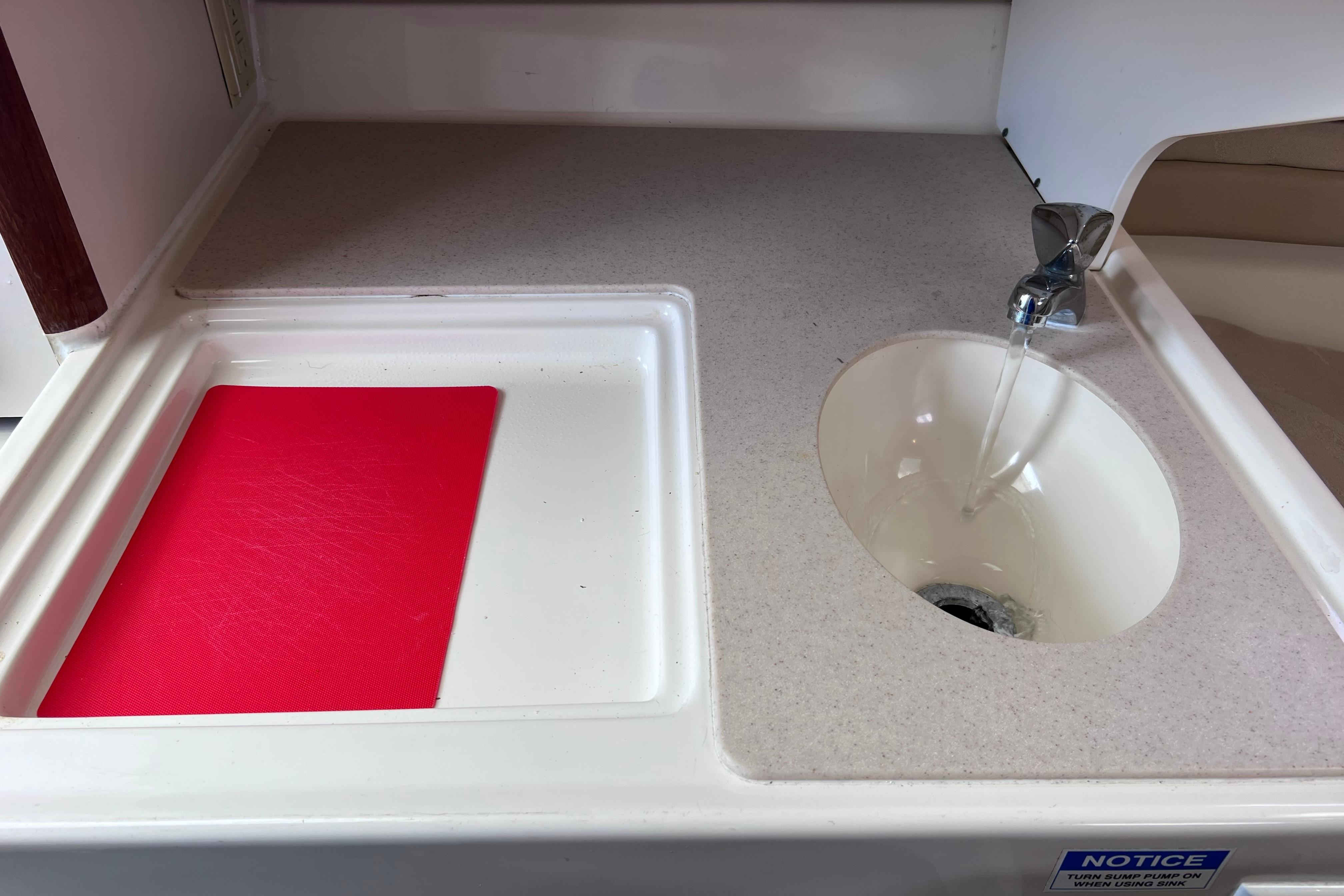 2004 Pursuit 2870 Walkaround boat sink with running water and red cutting board.