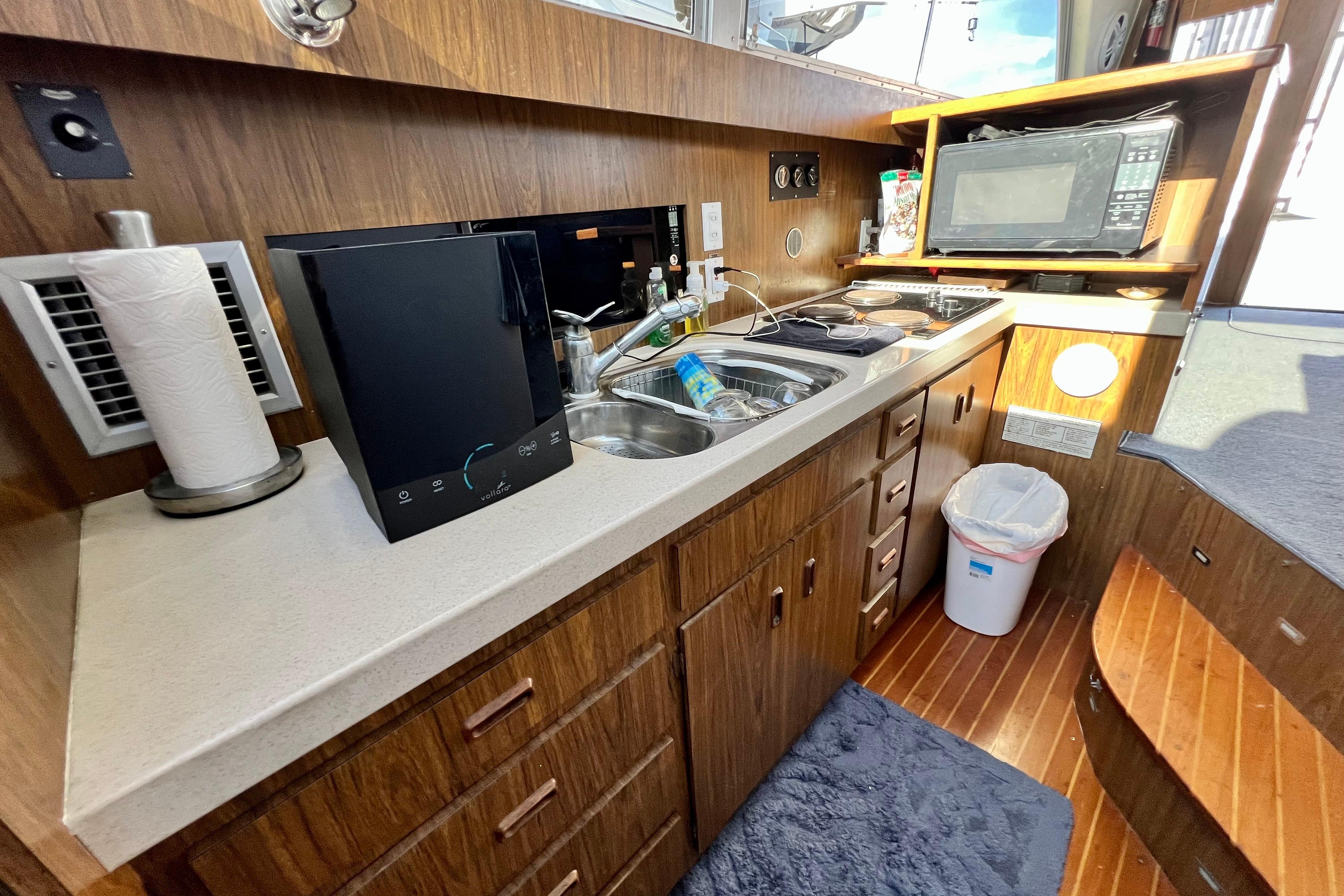 1982 Bertram 46 Convertible yacht kitchen with wood cabinetry, sink, and microwave.