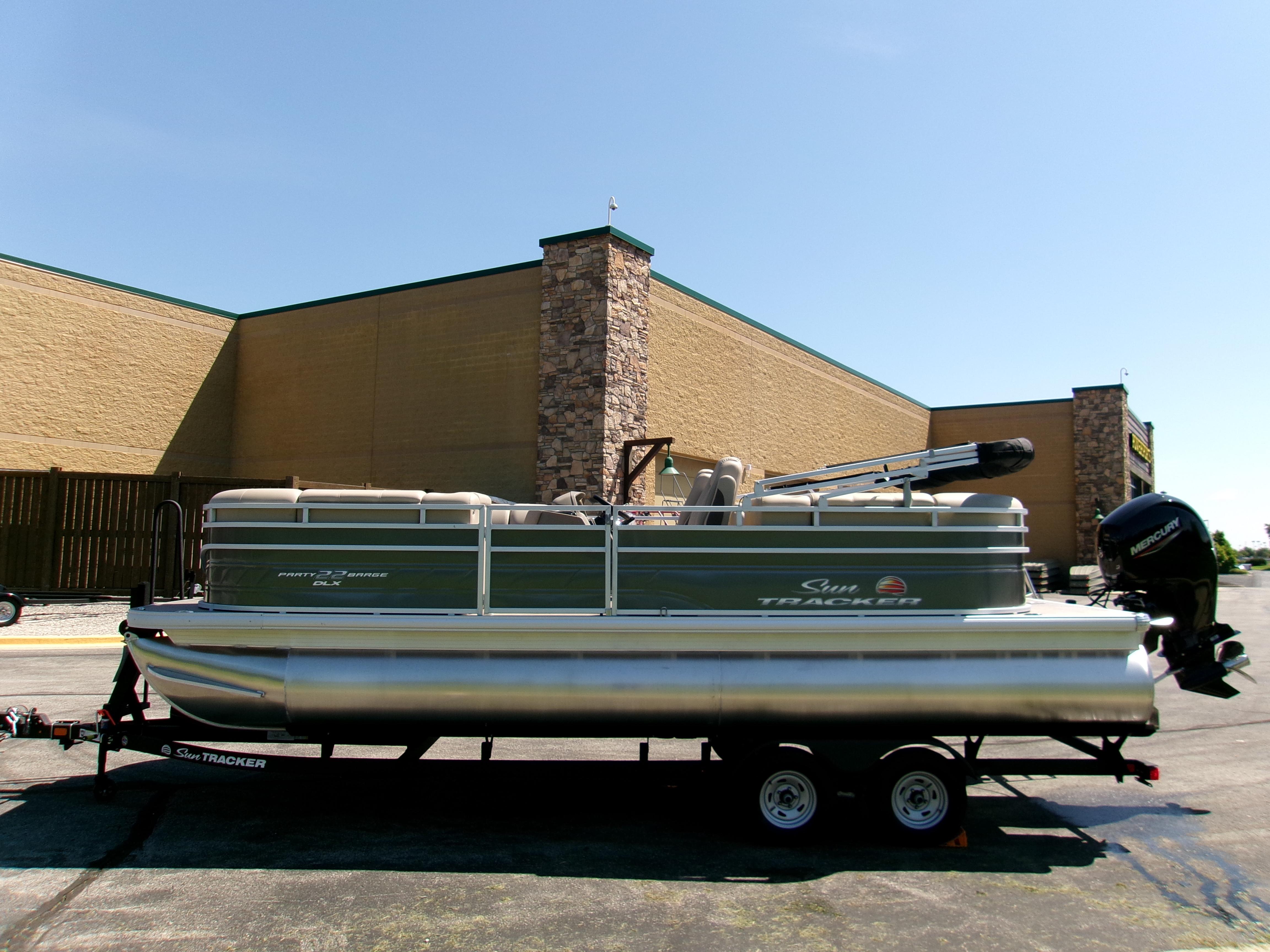 2025 Sun Tracker Party Barge 22 DLX pontoon boat on trailer, parked outdoors.
