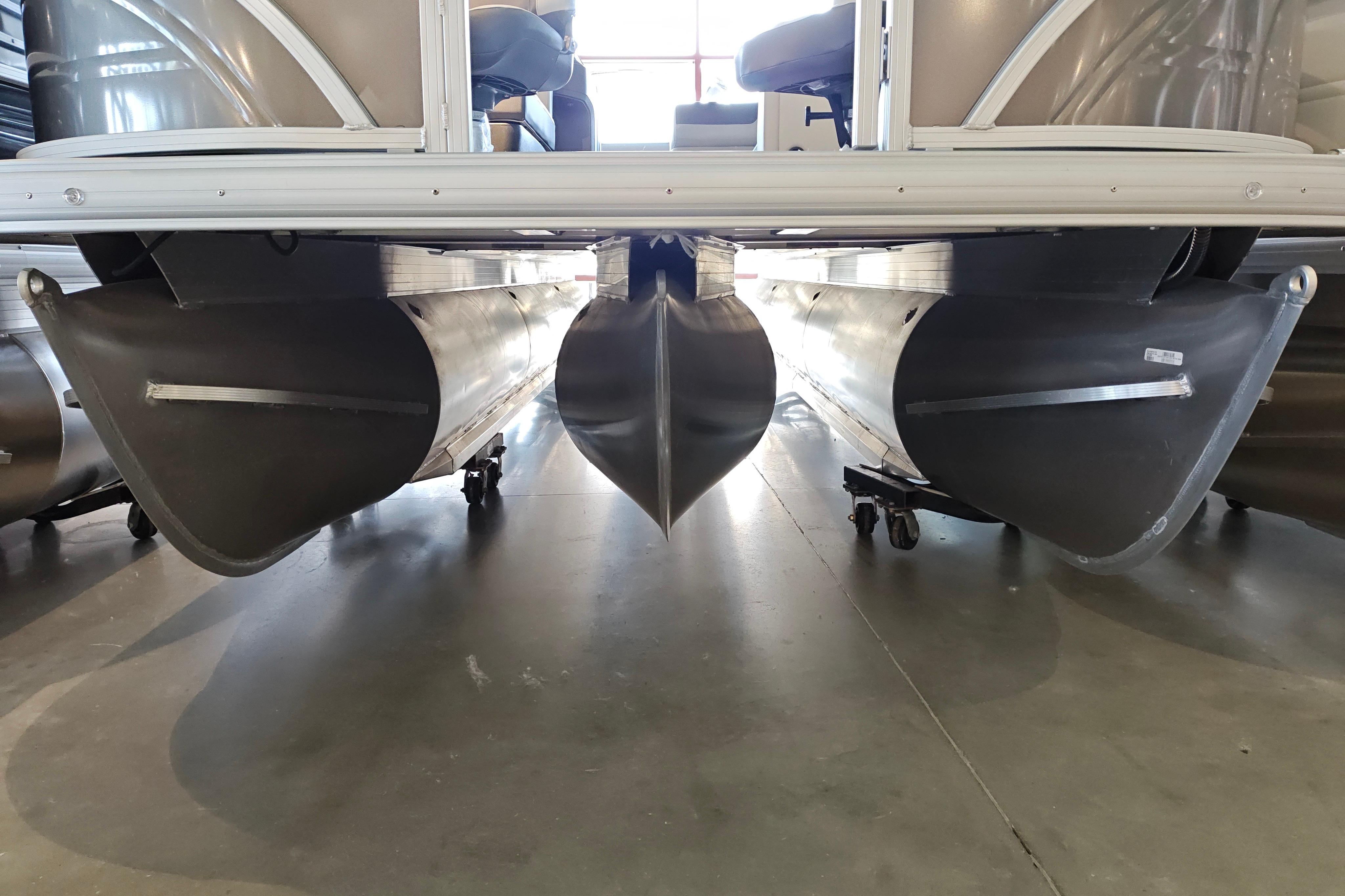 2026 Sun Tracker Fishin' Barge 22 XP3 pontoon boat hulls on display in showroom.