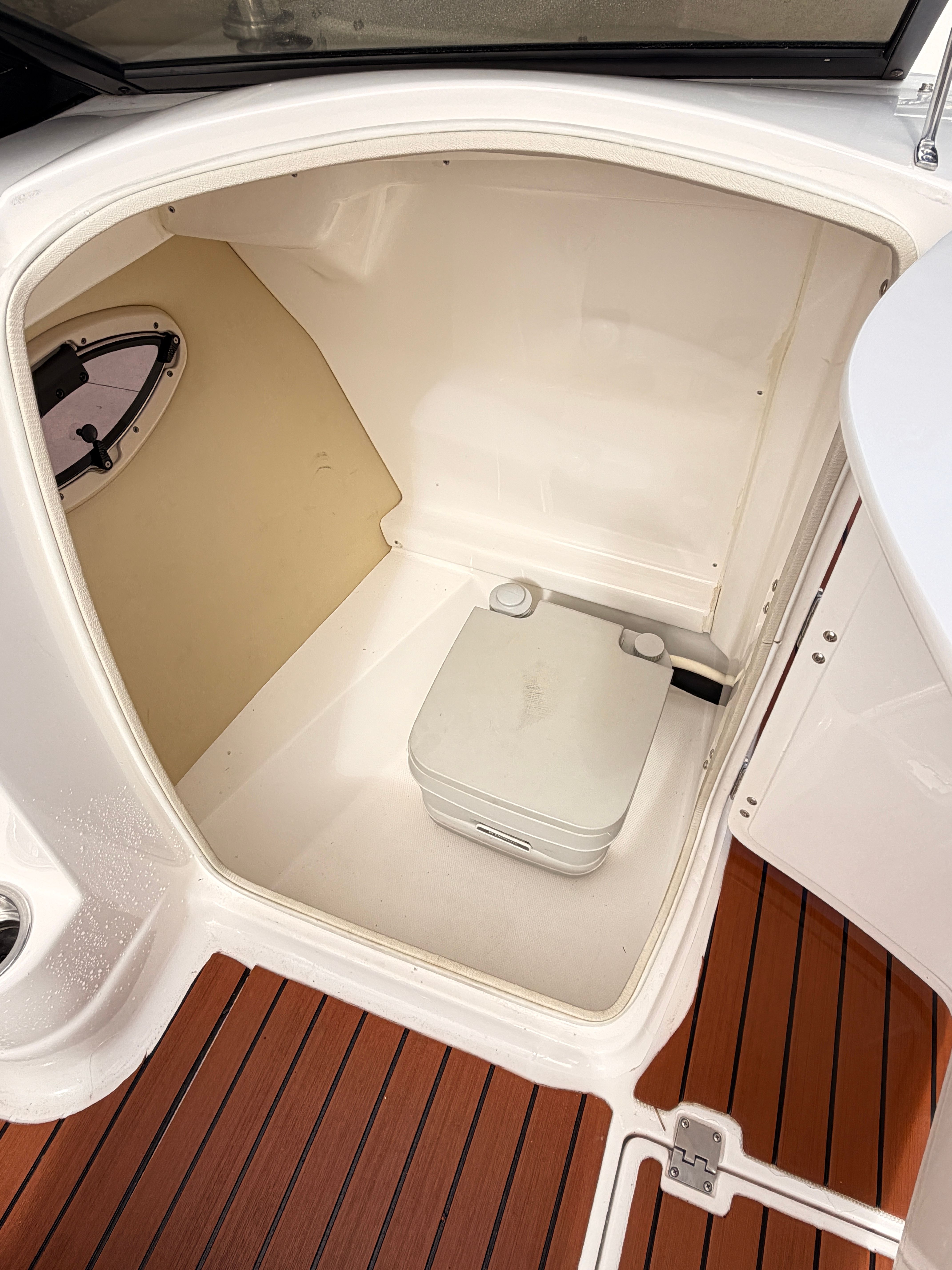 The image shows a small cabin with a portable toilet on a boat.