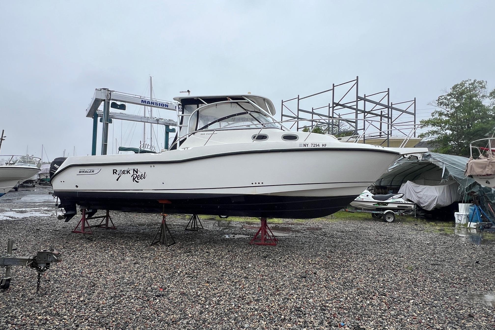 2005 Boston Whaler 305 Conquest boat on stands in a marina setting.
