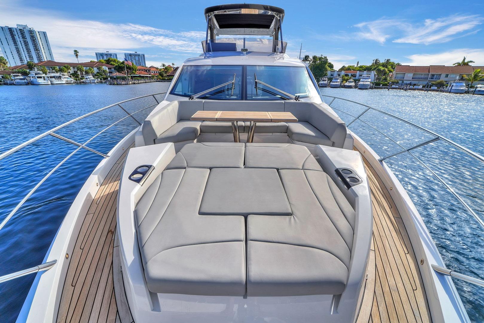 2023 Sunseeker Manhattan 68 yacht with luxurious deck seating on a sunny waterfront.