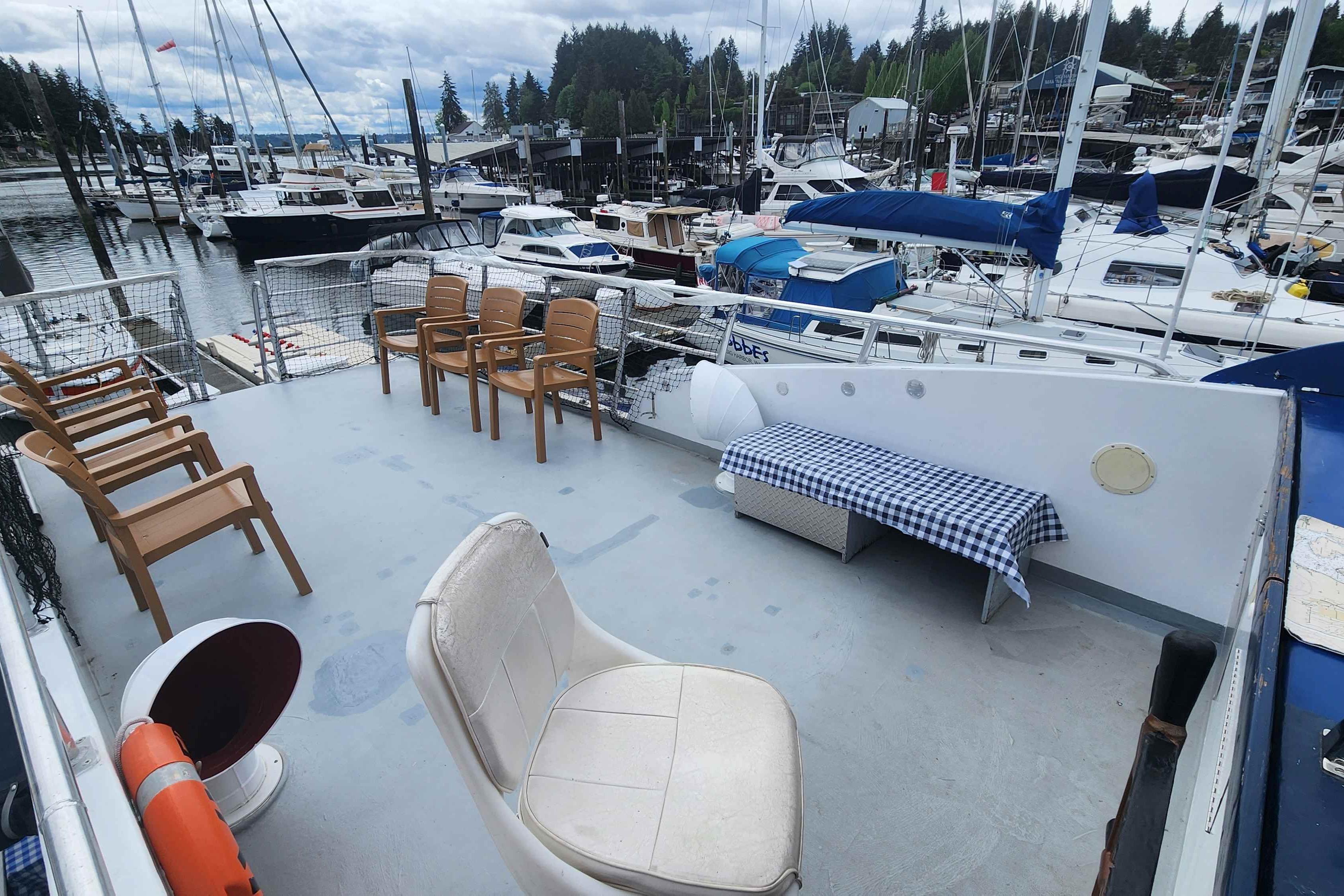 Upper deck of a 1964 Grandy Tour Boat with seating, docked at a marina.