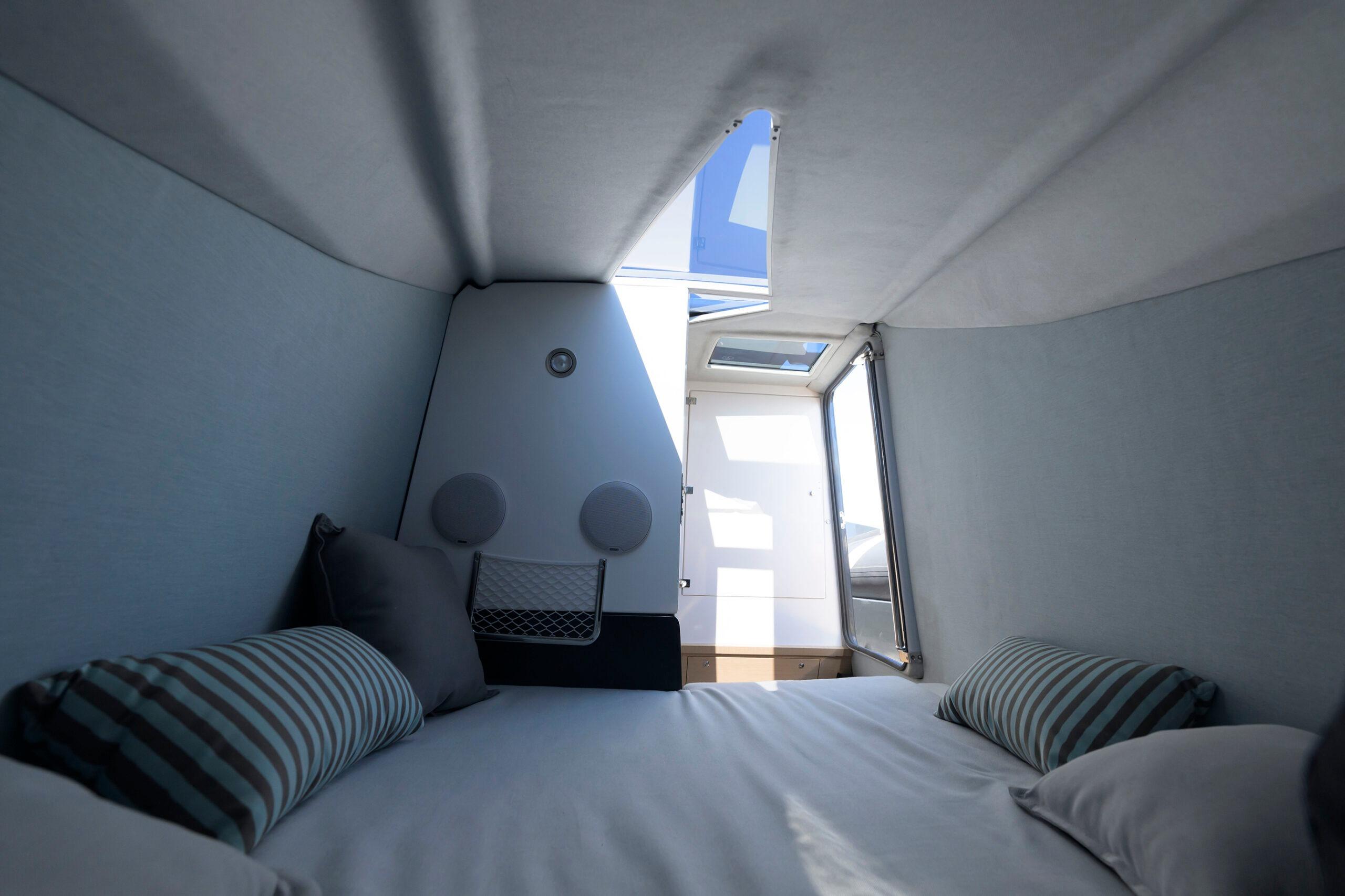 2024 Tropida Cosmic 39 cabin interior with skylight, cozy bedding, and striped pillows.