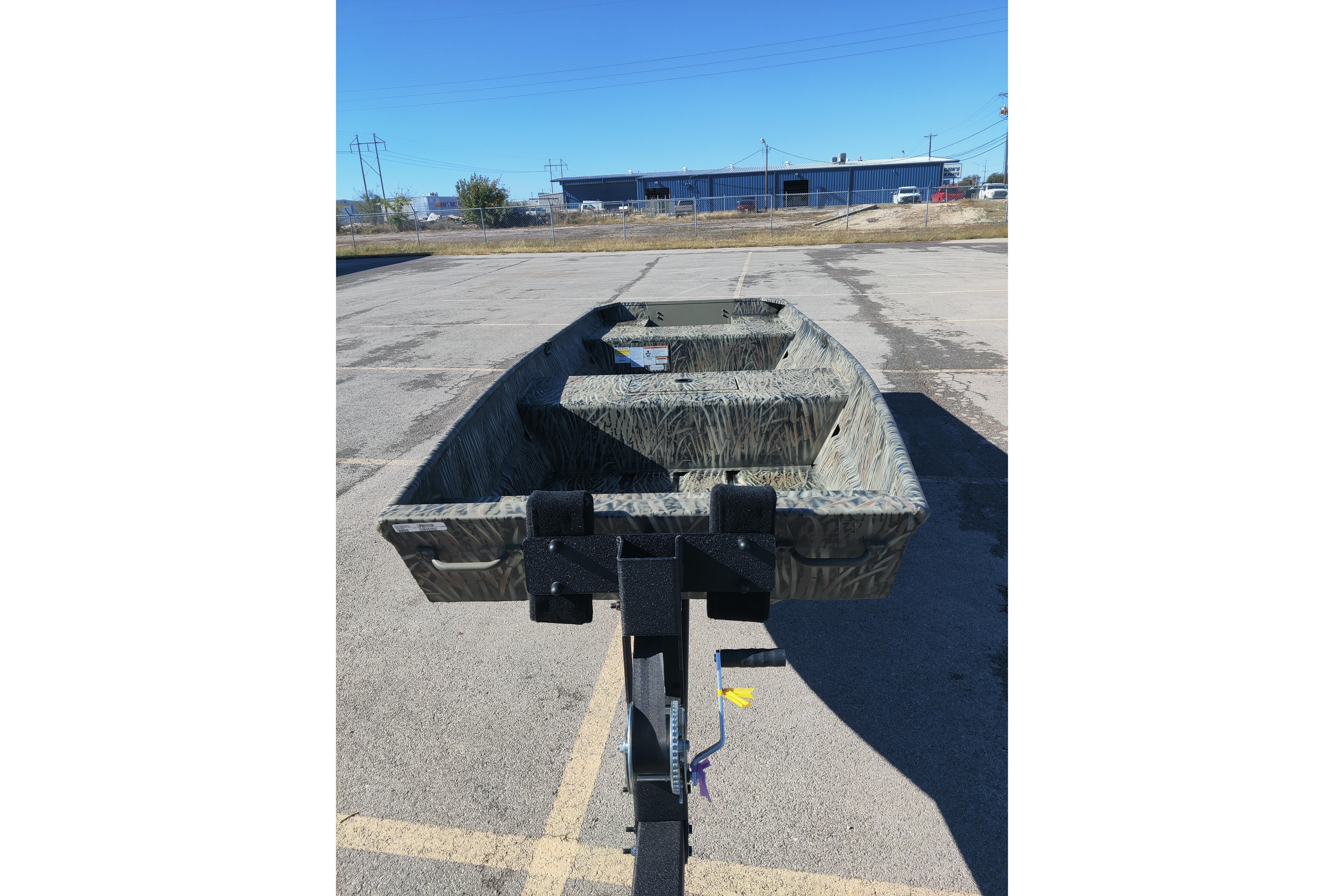 2026 Tracker Grizzly 15 Jon boat on trailer in parking lot, clear sky background.
