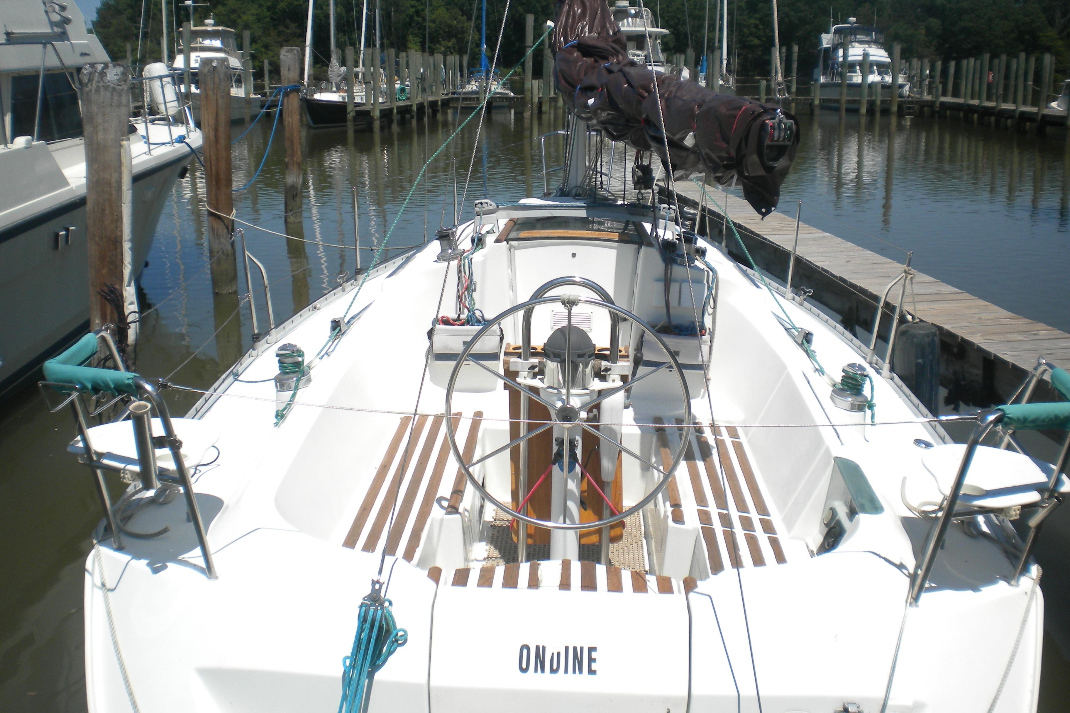 1994 Beneteau First 310 sailboat docked at marina, featuring spacious cockpit and steering wheel.