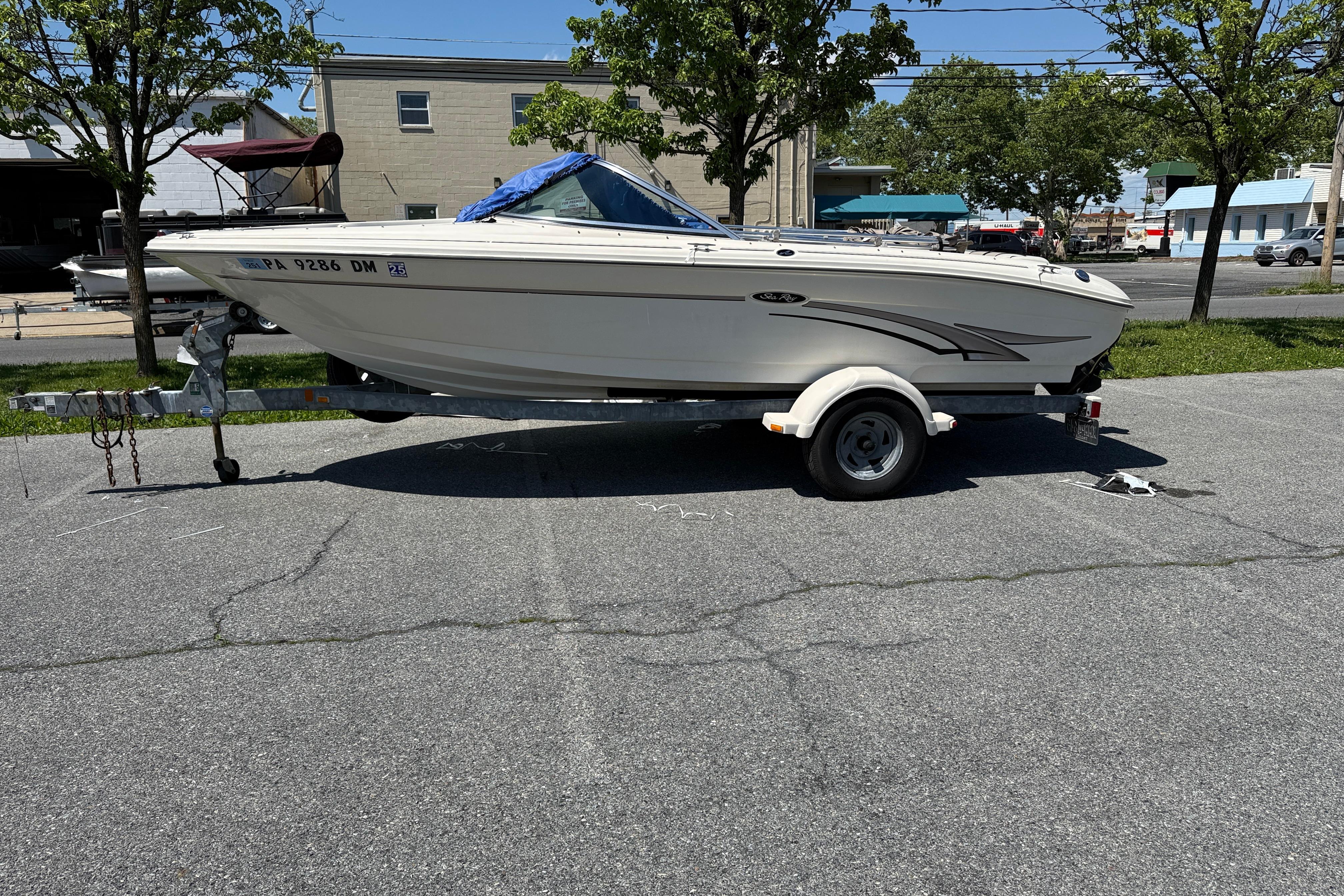 2003 Sea Ray 182 Bow Rider boat on trailer in parking lot, sunny day.