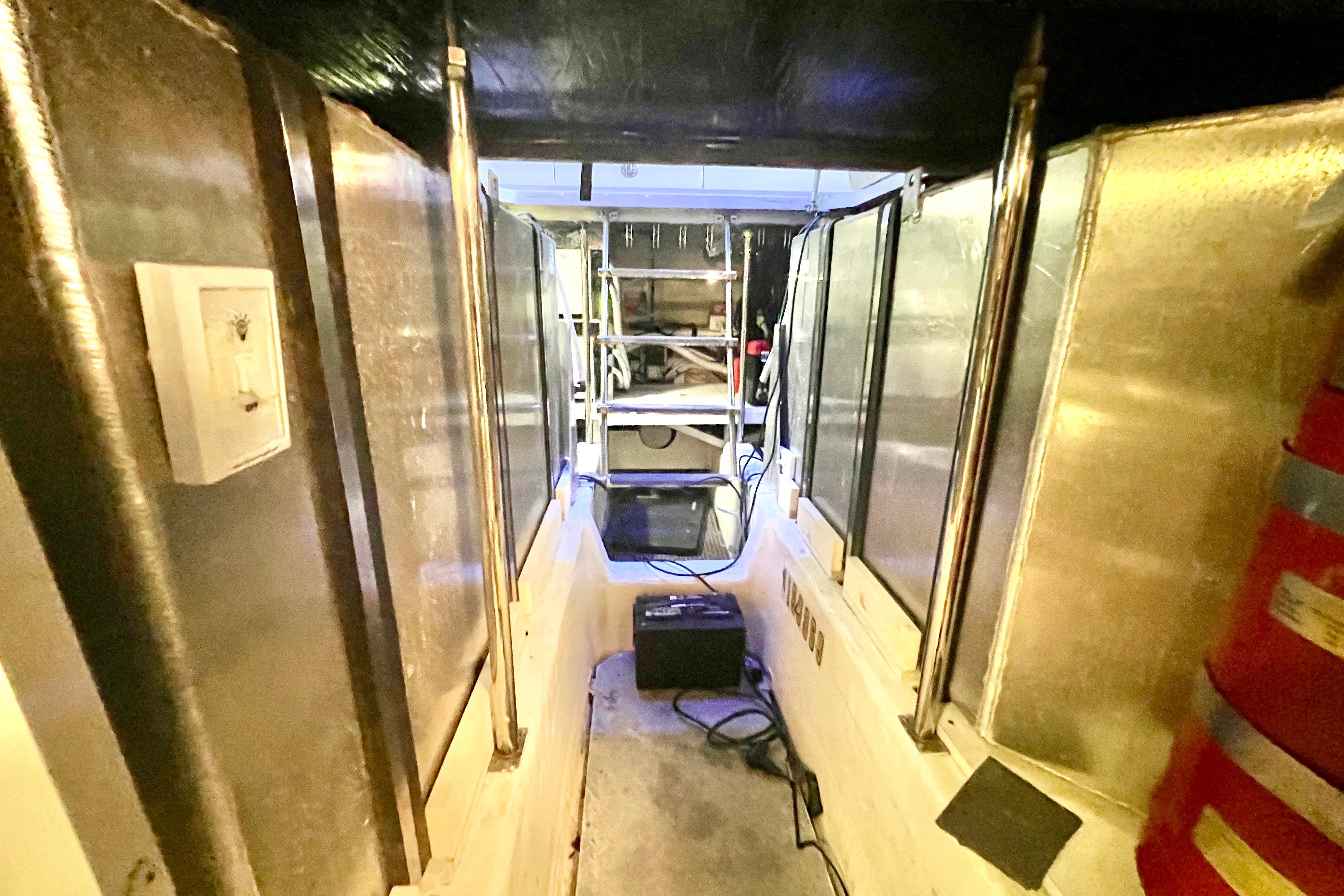 Engine room of a 2005 Carver 56 Voyager yacht, featuring metallic surfaces and equipment.