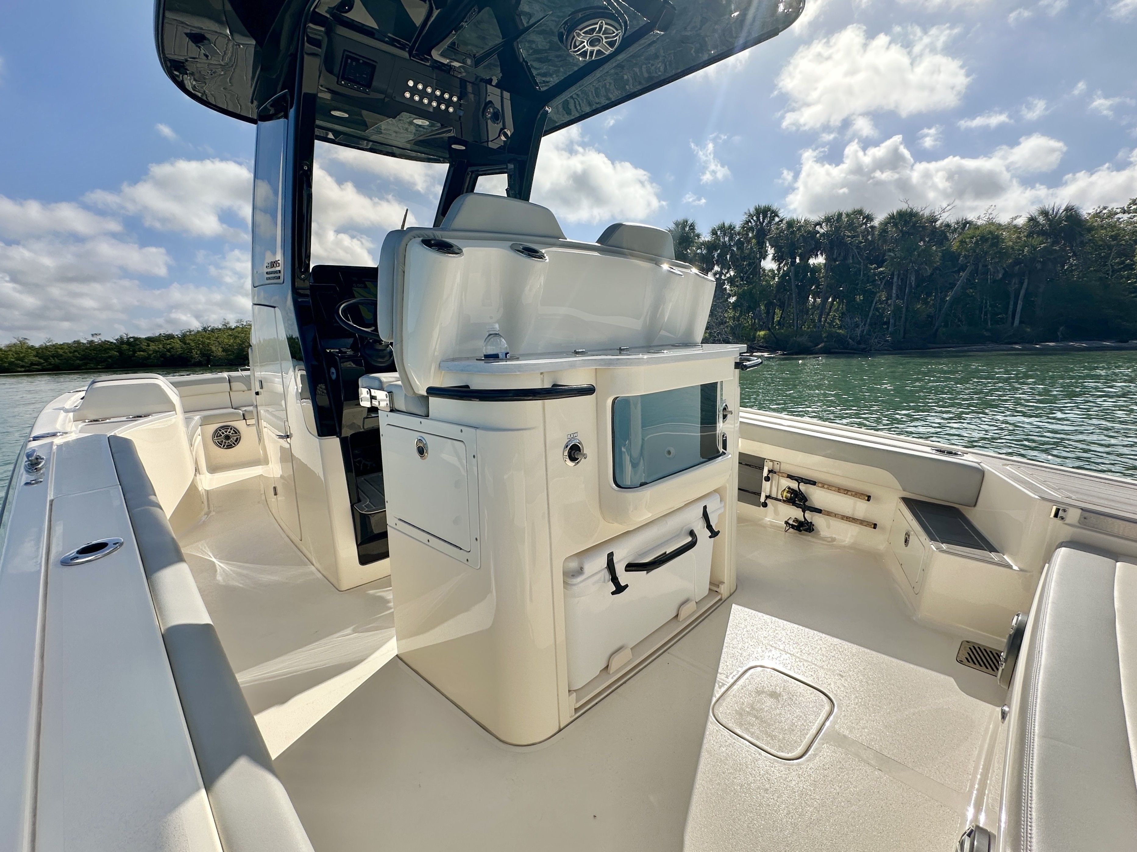 The image shows the cockpit of a 2024 Scout 281 XSS boat on calm water with trees in the background.