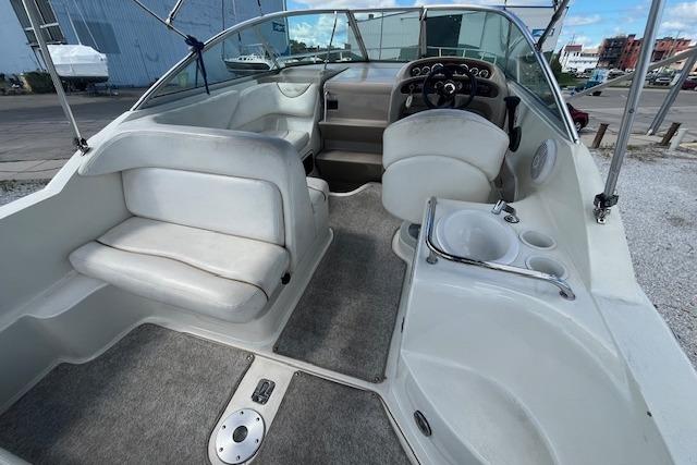 2003 Sea Ray 260 Sundancer boat interior with seating and helm, docked outdoors.