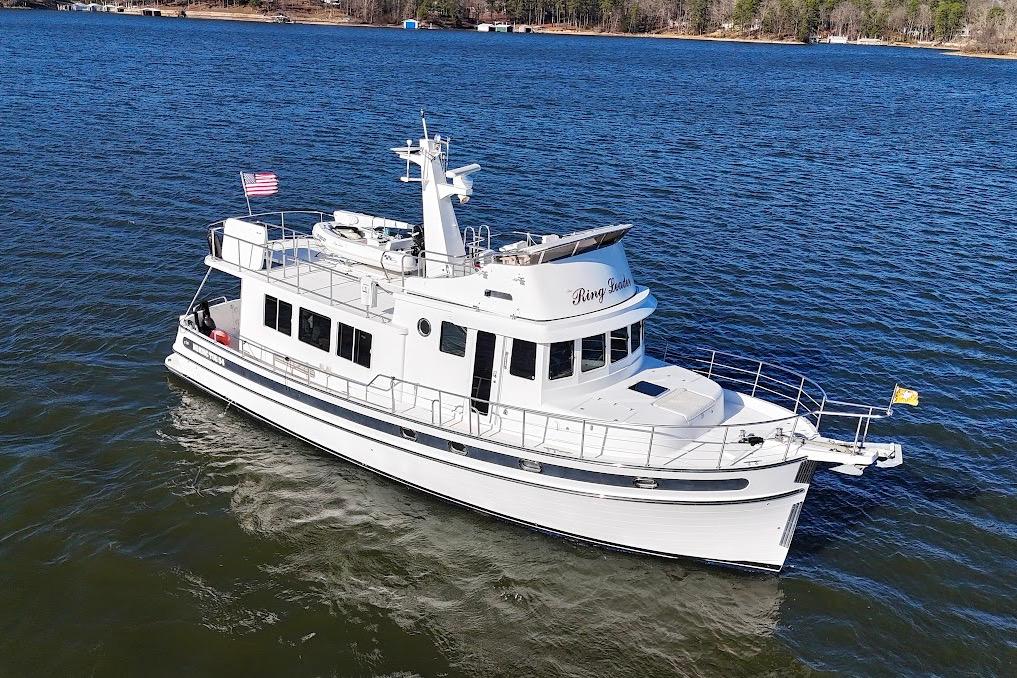 2007 Nordic Tug 54 cruising on a serene lake with clear blue water.
