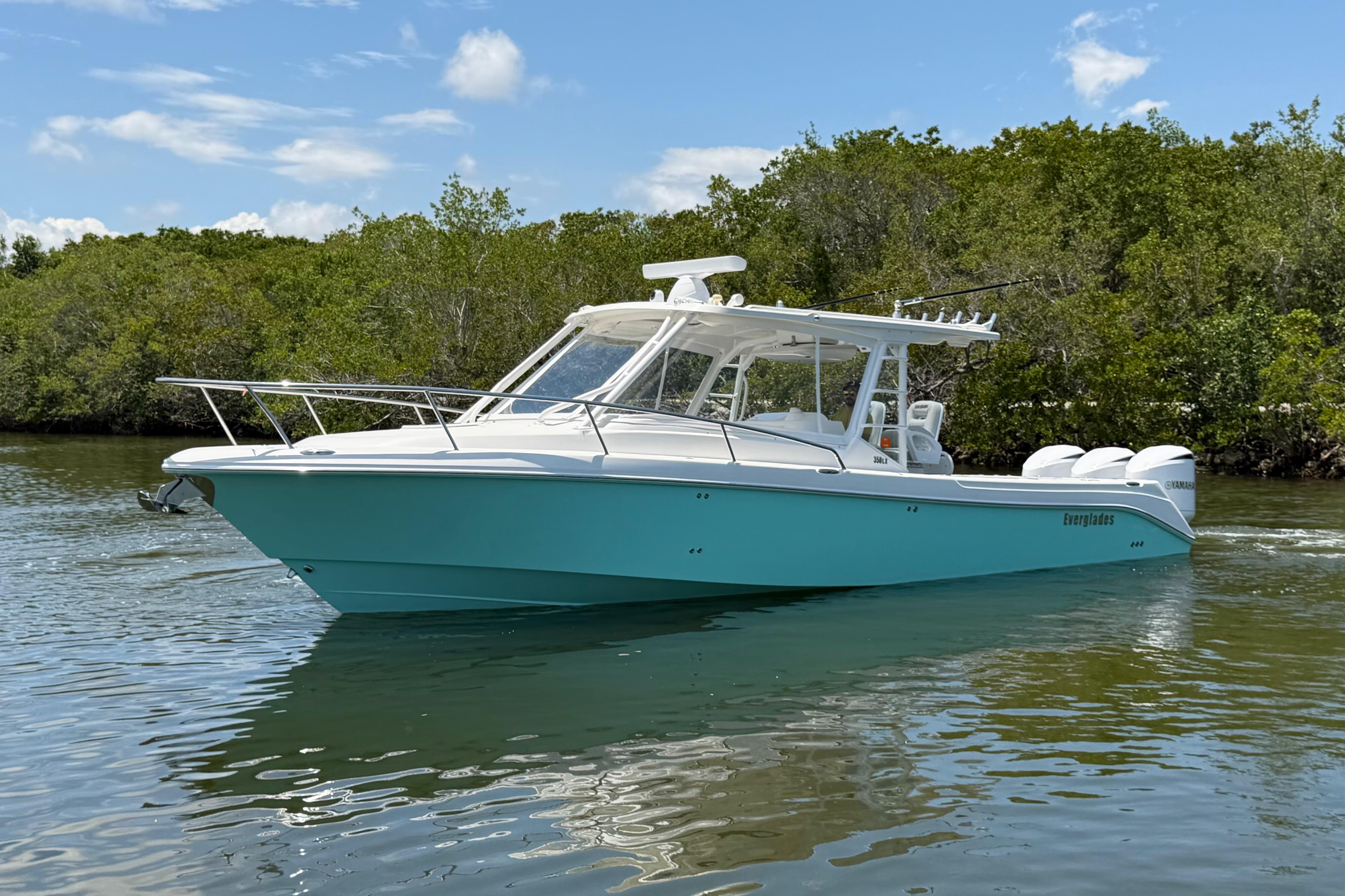 2009 Everglades 350LX boat cruising on calm water near lush greenery.
