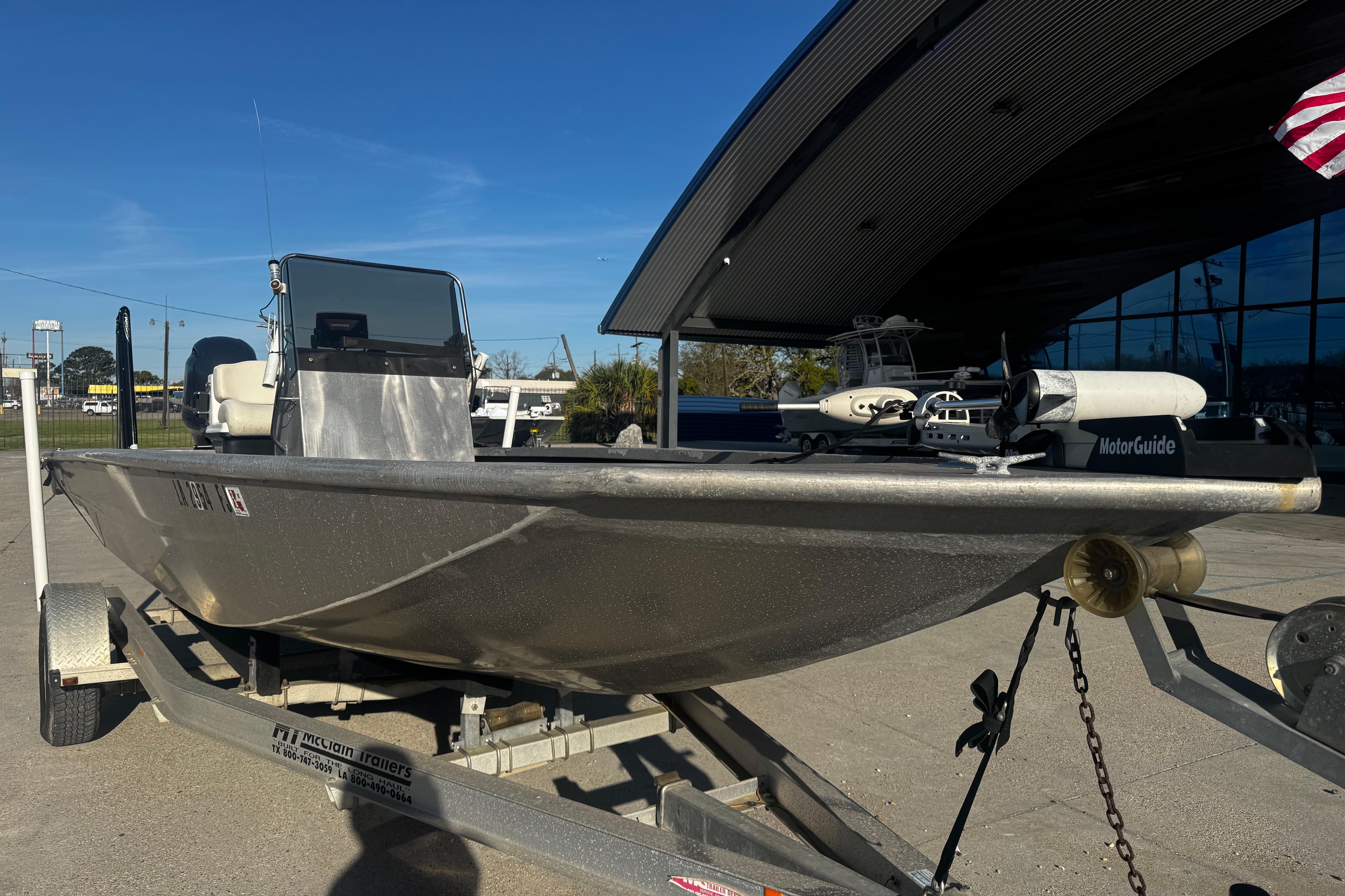 Custom Charles Leonard 21 boat on trailer, 2004 model, parked outdoors under clear blue sky.