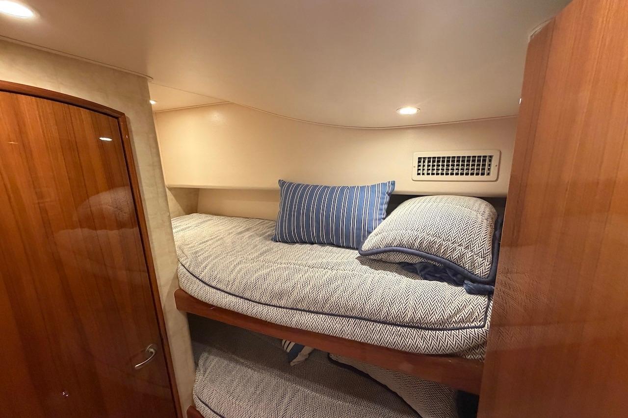 Cozy cabin interior of 2012 Viking 50 Convertible yacht with bunk beds and striped pillows.
