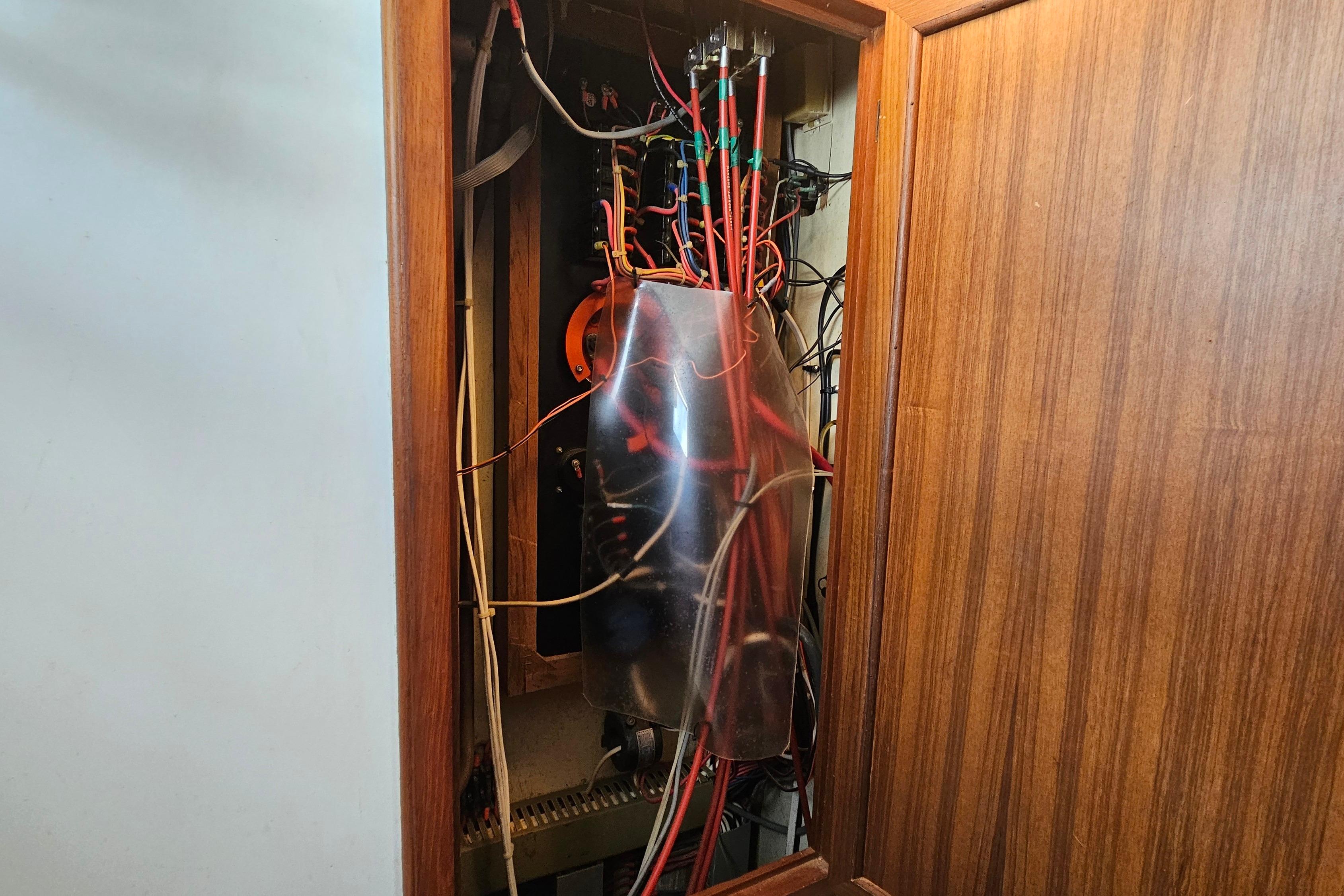 Electrical panel with wiring inside a wooden cabinet on a 1988 Overseas Monk 42.