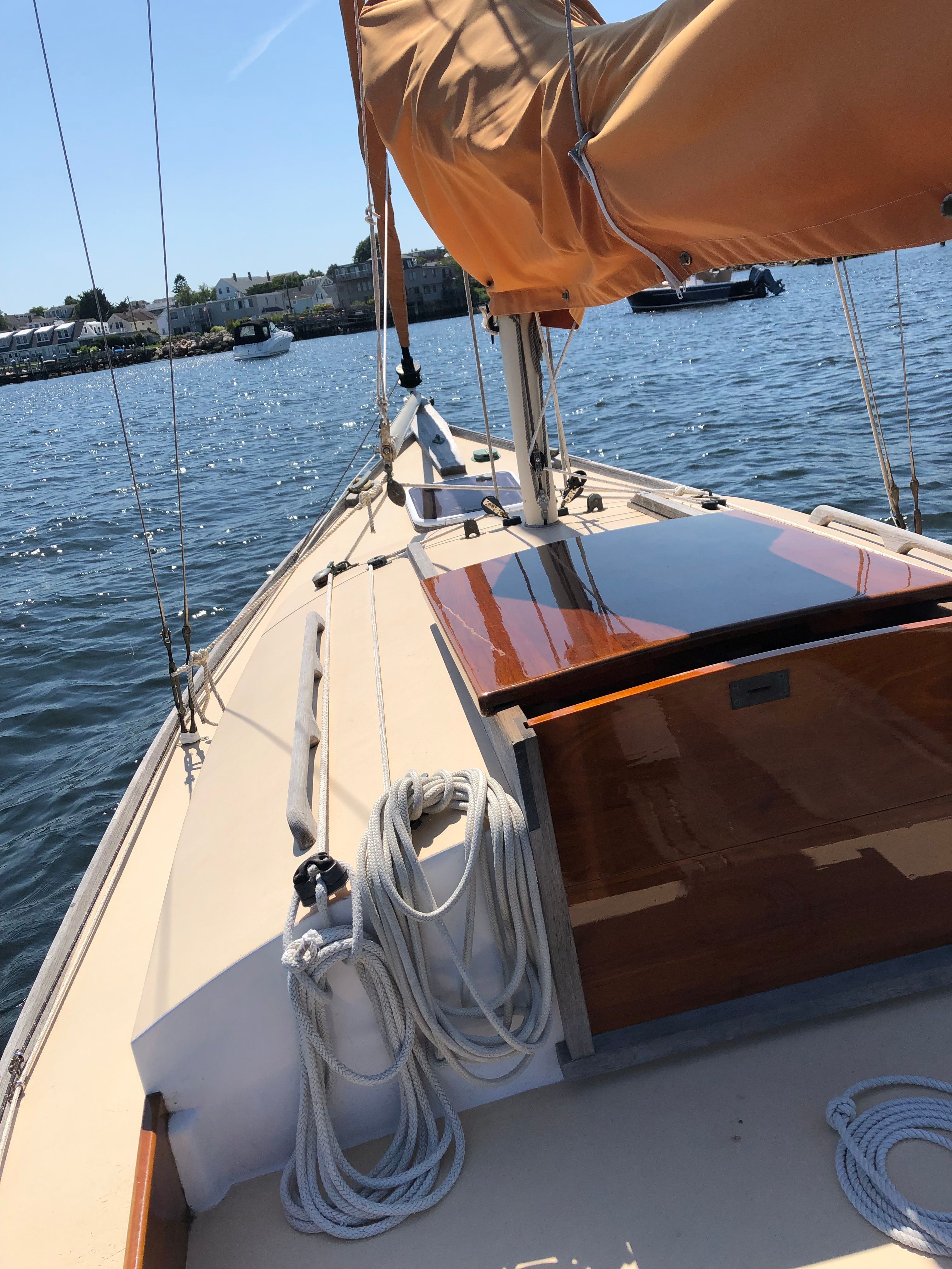 A sailboat with an orange sail on calm water.